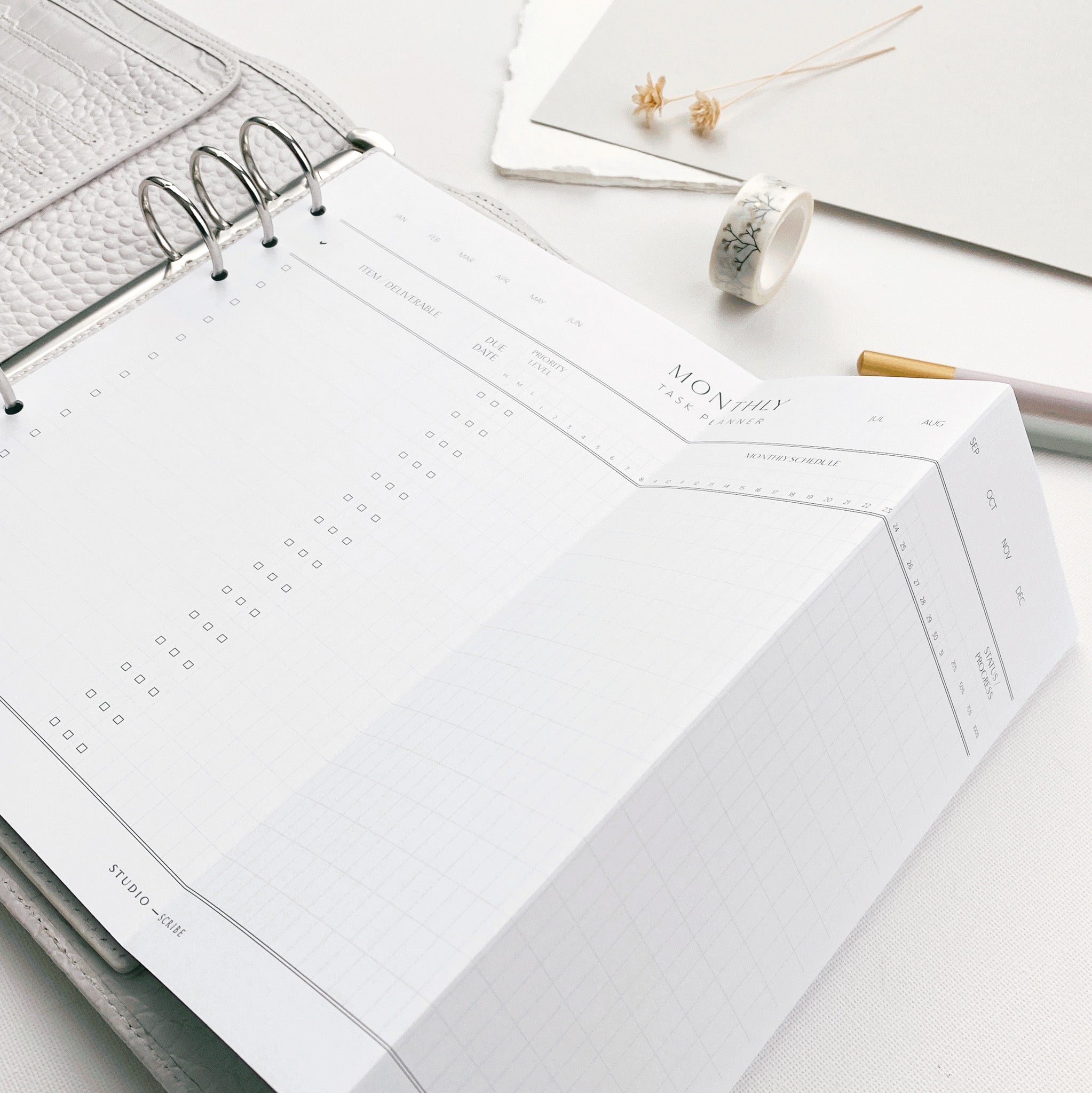Printed A4 planner refill page folded to fit an A5 organiser, surrounded by various stationery items