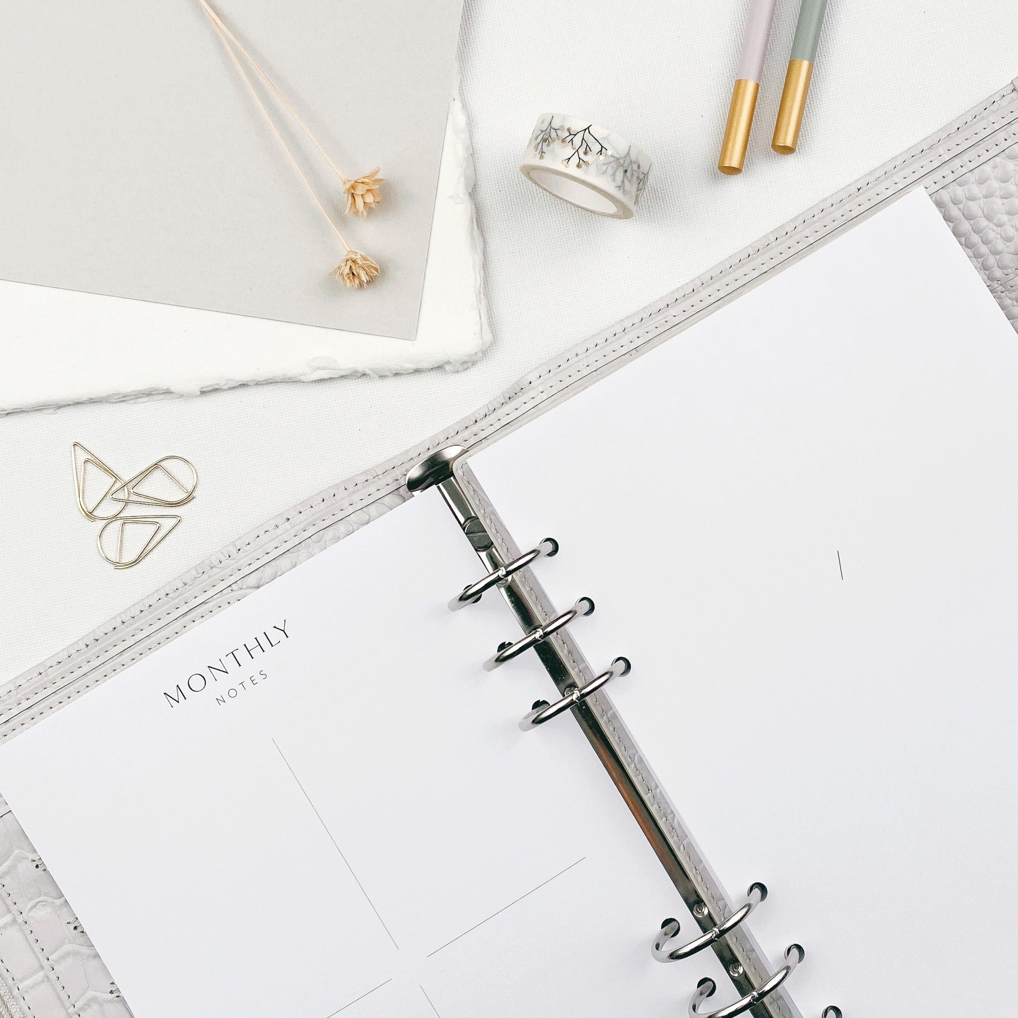 Undated A5 monthly calendar pages open in a personal organiser on a white desk