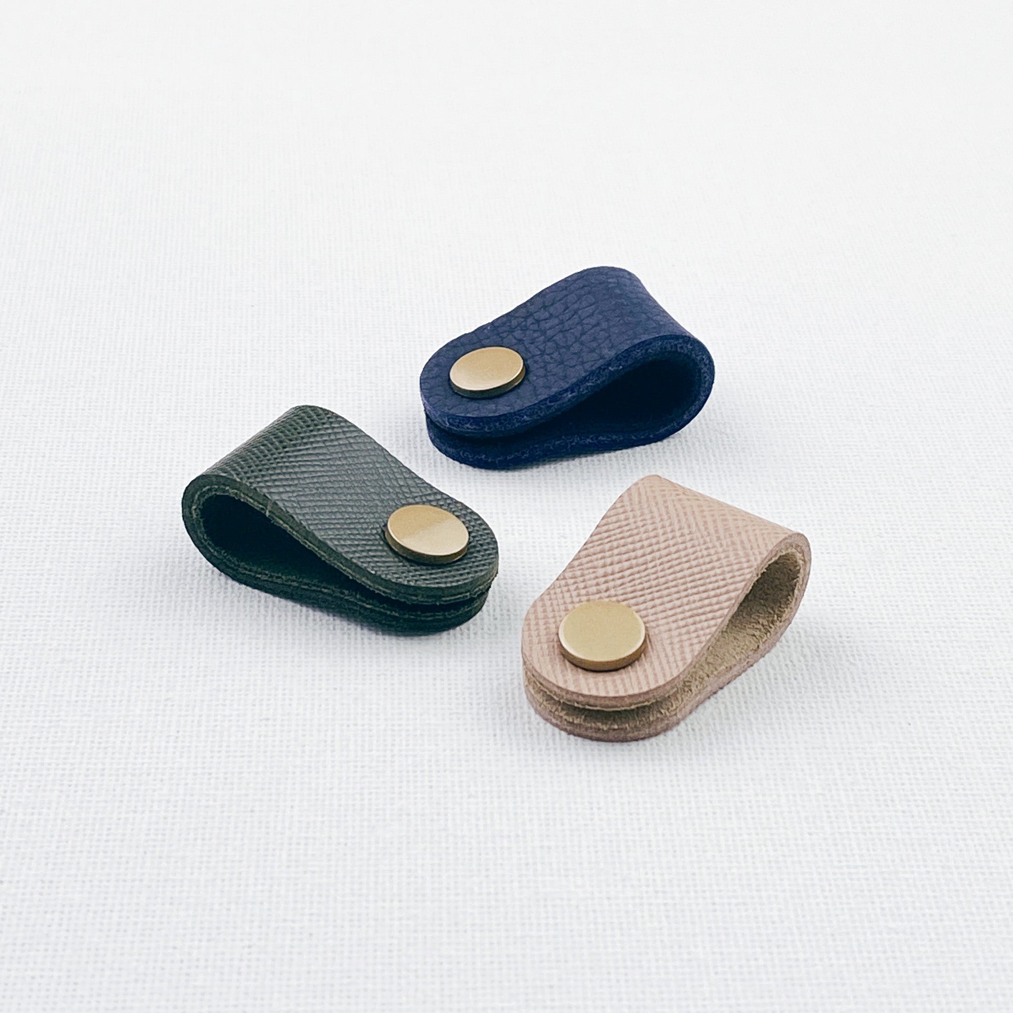 Set of 3 cord keepers in green, navy and nude colours with a gold snap