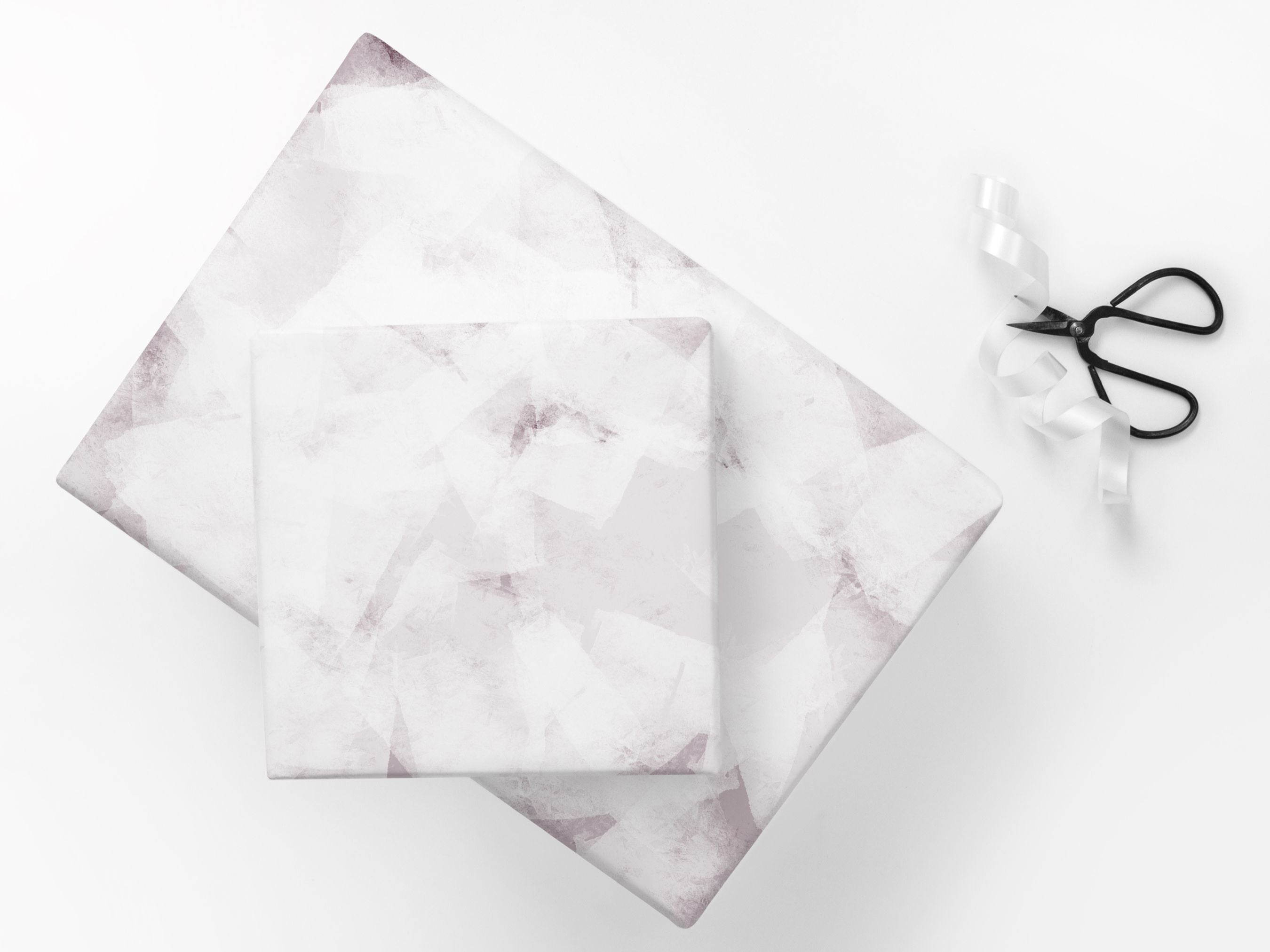 Set of 2 gifts wrapped in a modern abstract paper next to scissors and ribbon