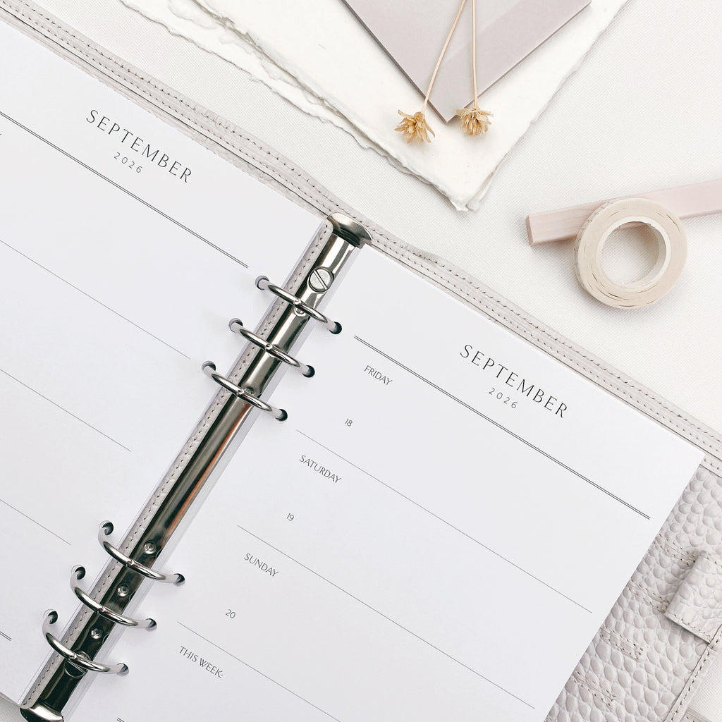 Weekly planner open to September with stationery items on a light surface.