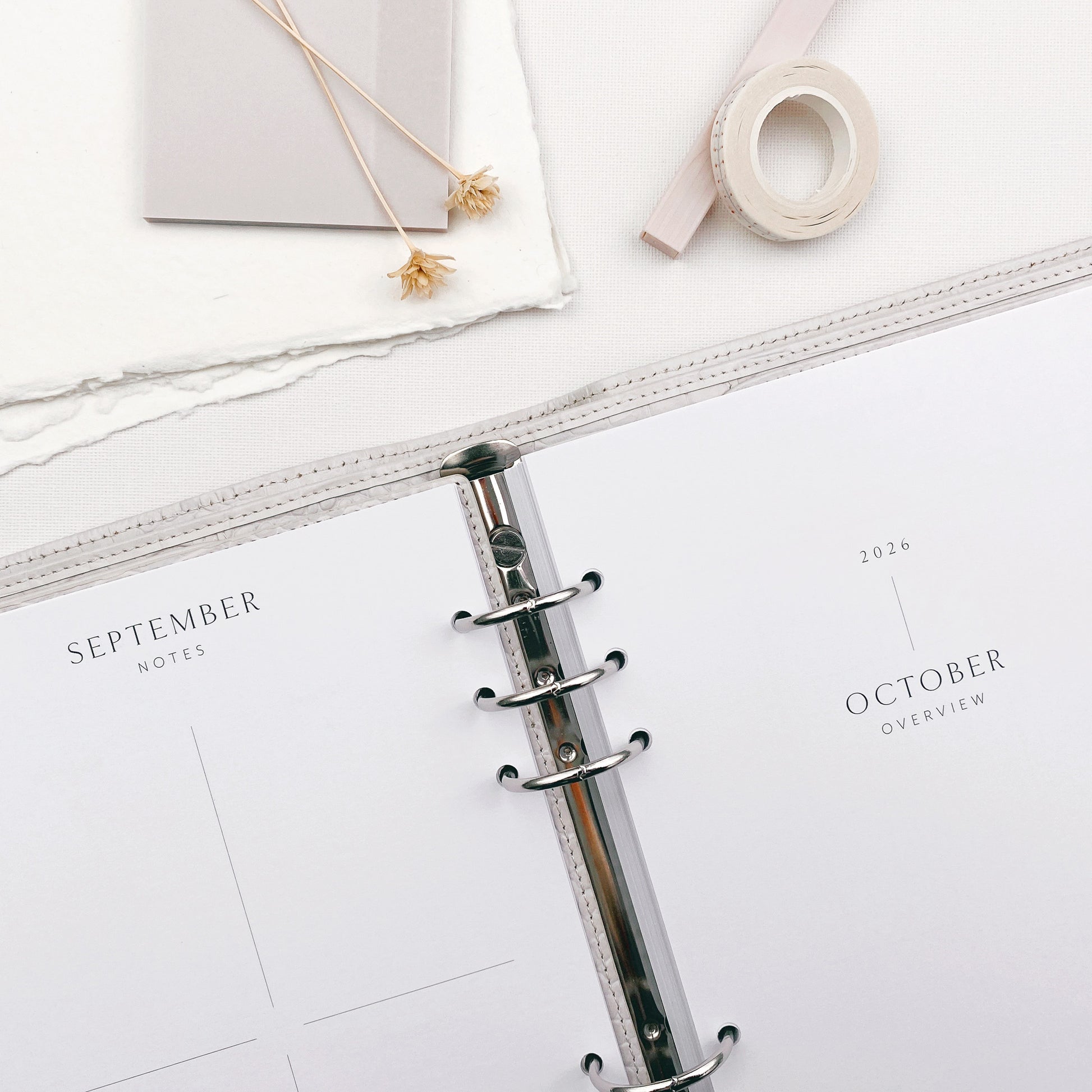 6 ring binder on a white surface with a planner open to September and October pages.