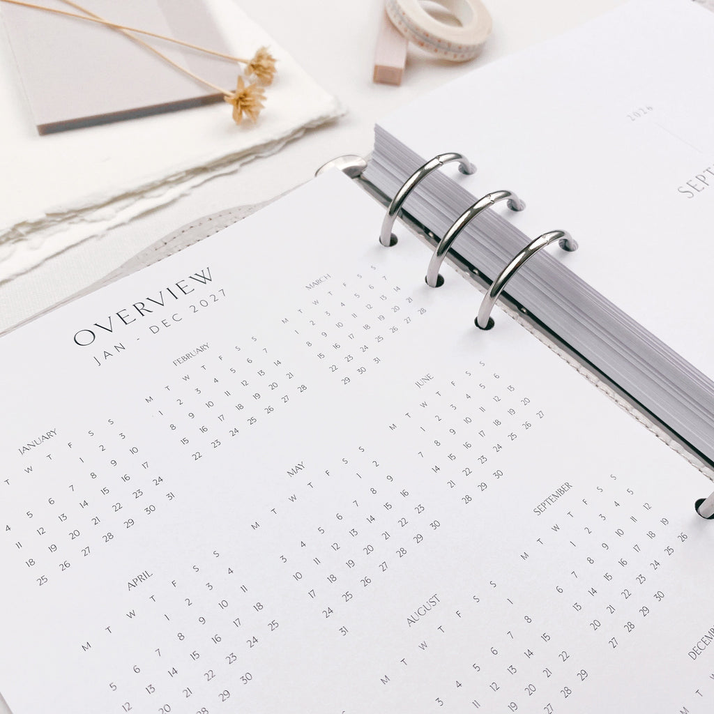 Calendar planner page within a 6 ring binder on a white surface.