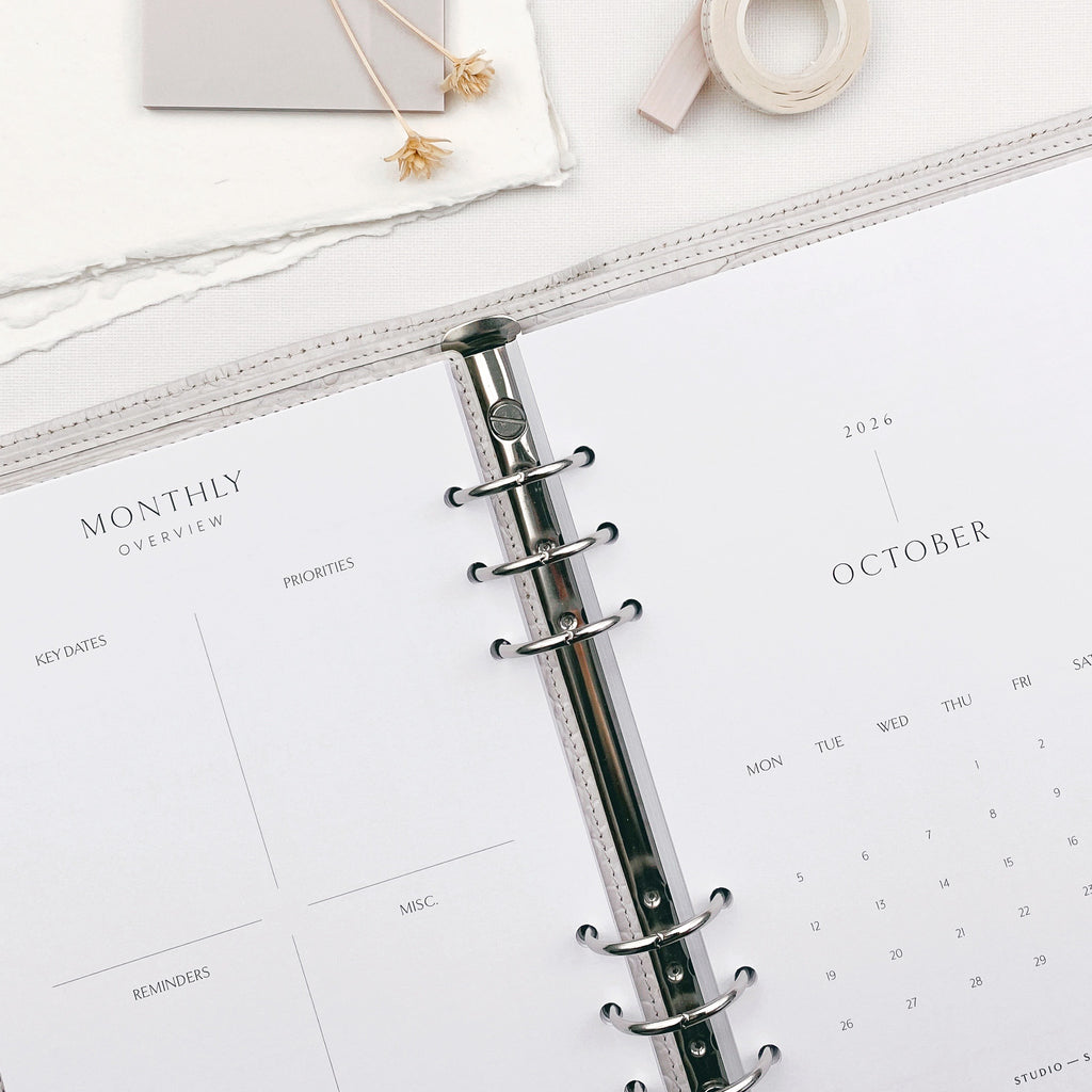 Planner within a 6 ring binding on a white surface with calendar pages