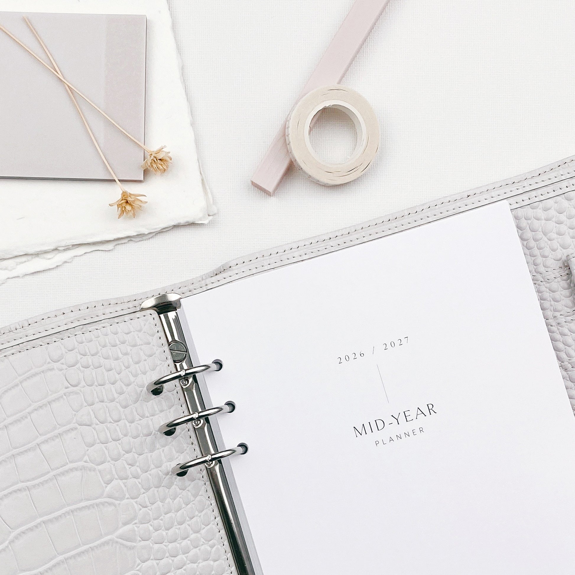 Grey planner with faux-croc texture cover and stationery items on a white background