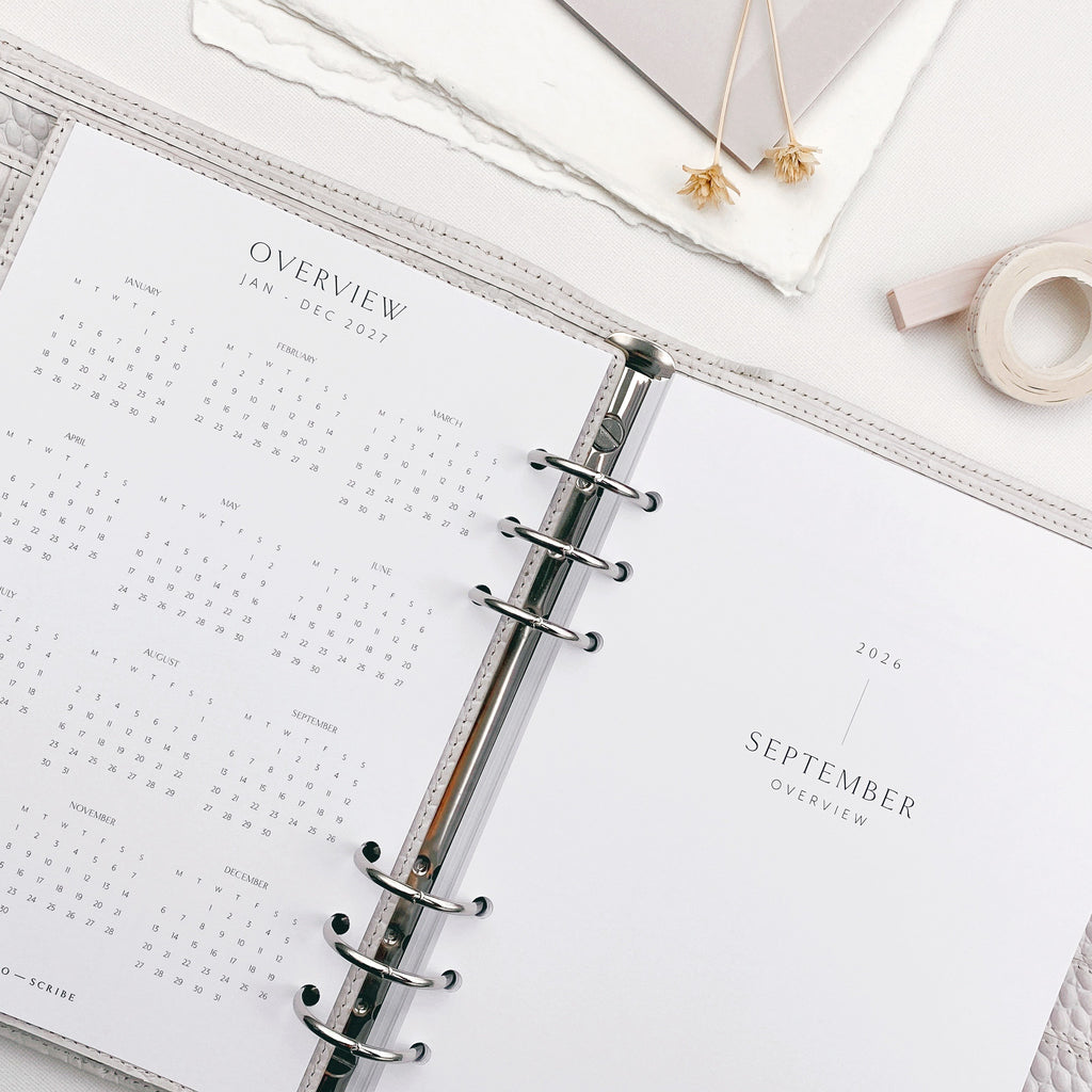 Open planner with a yearly overview and September title page, surrounded by stationery items.