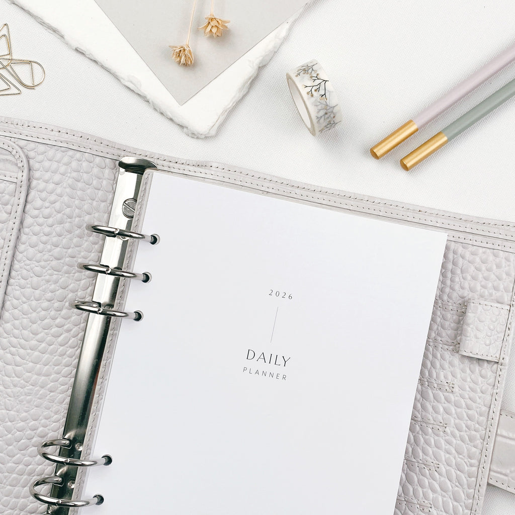 Daily planner refill pages in an open organiser on a white surface