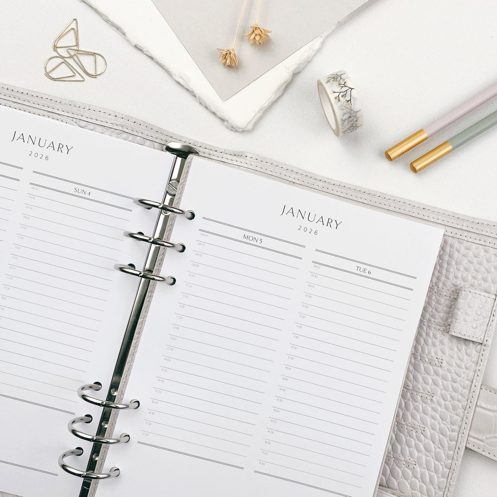 Open planner with daily layout, dipped pencils, and washi tape on a white surface.