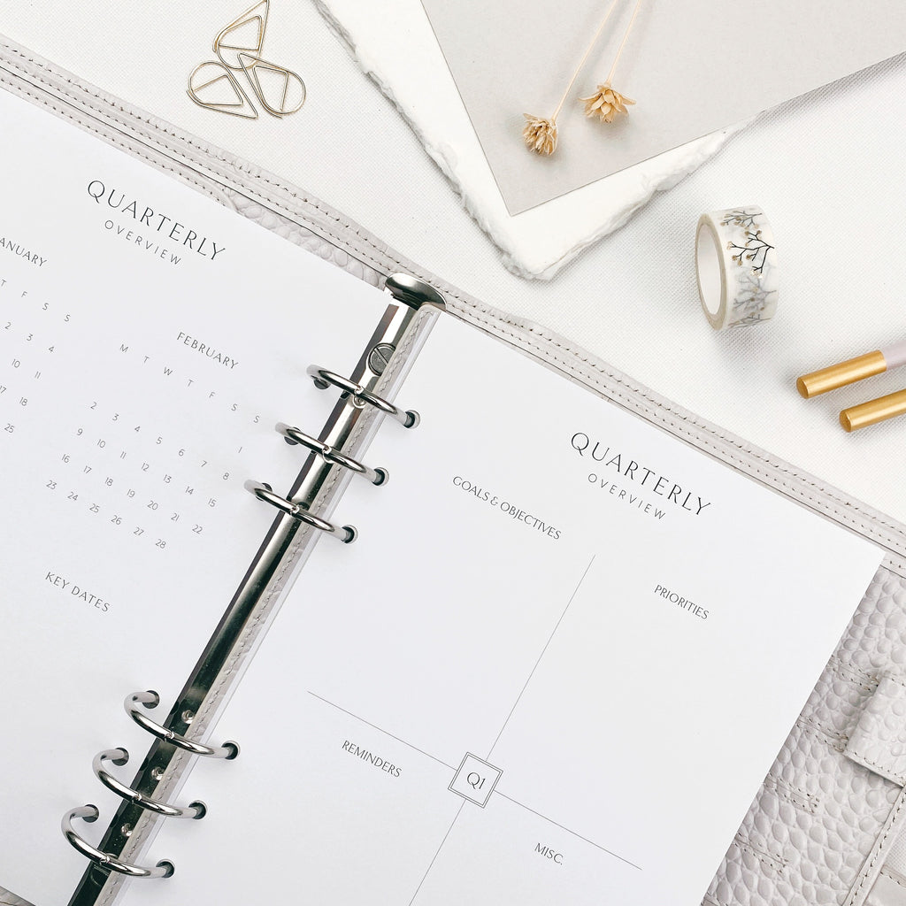 Planner with quarterly overview pages on a white surface with stationery items.