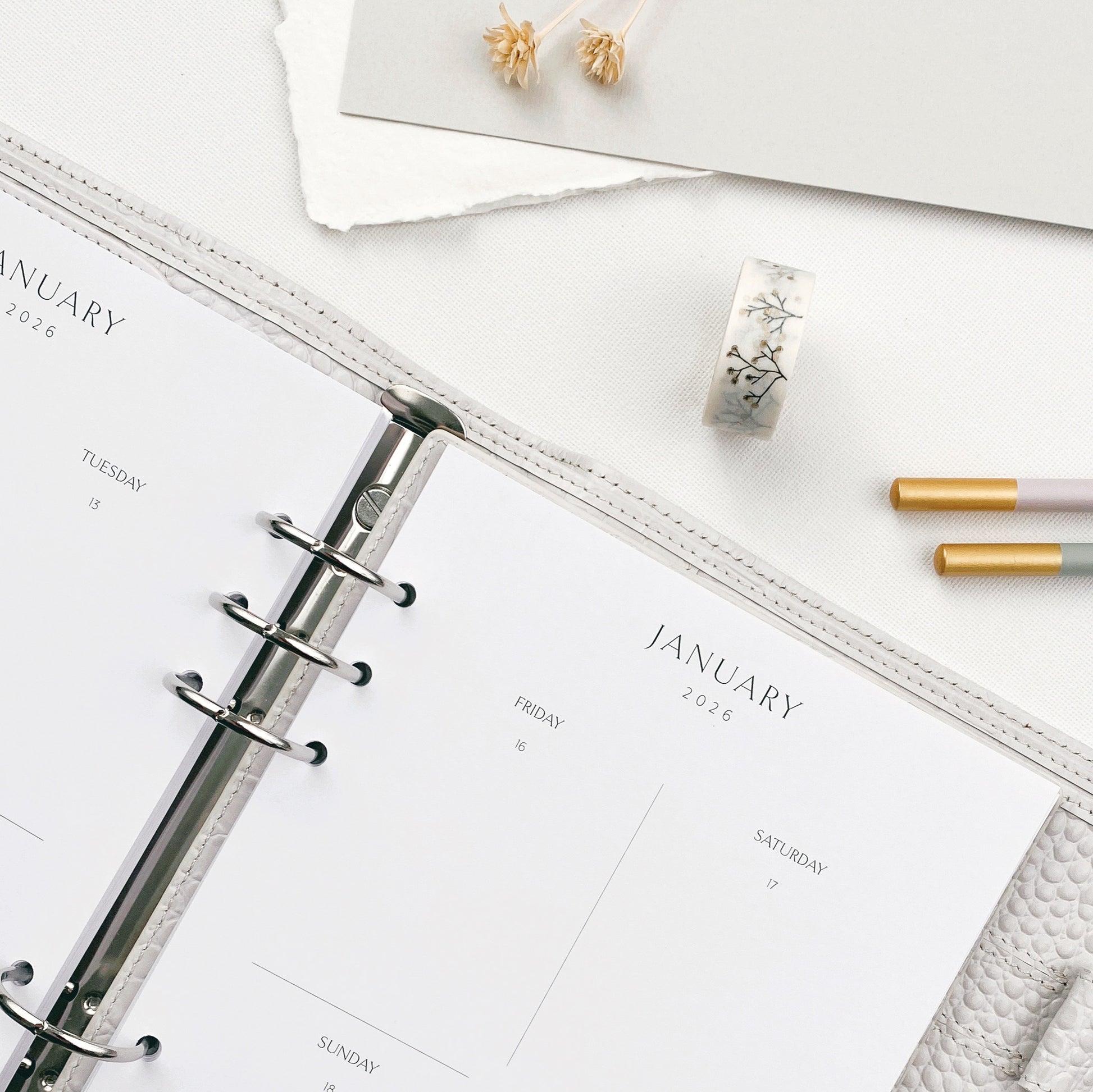 Open planner with January weekly layout and stationery on a white surface