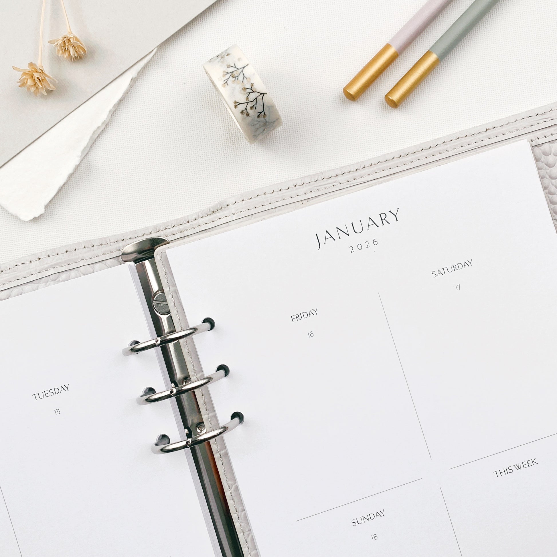 Weekly planner with January view on a white surface with stationery items.