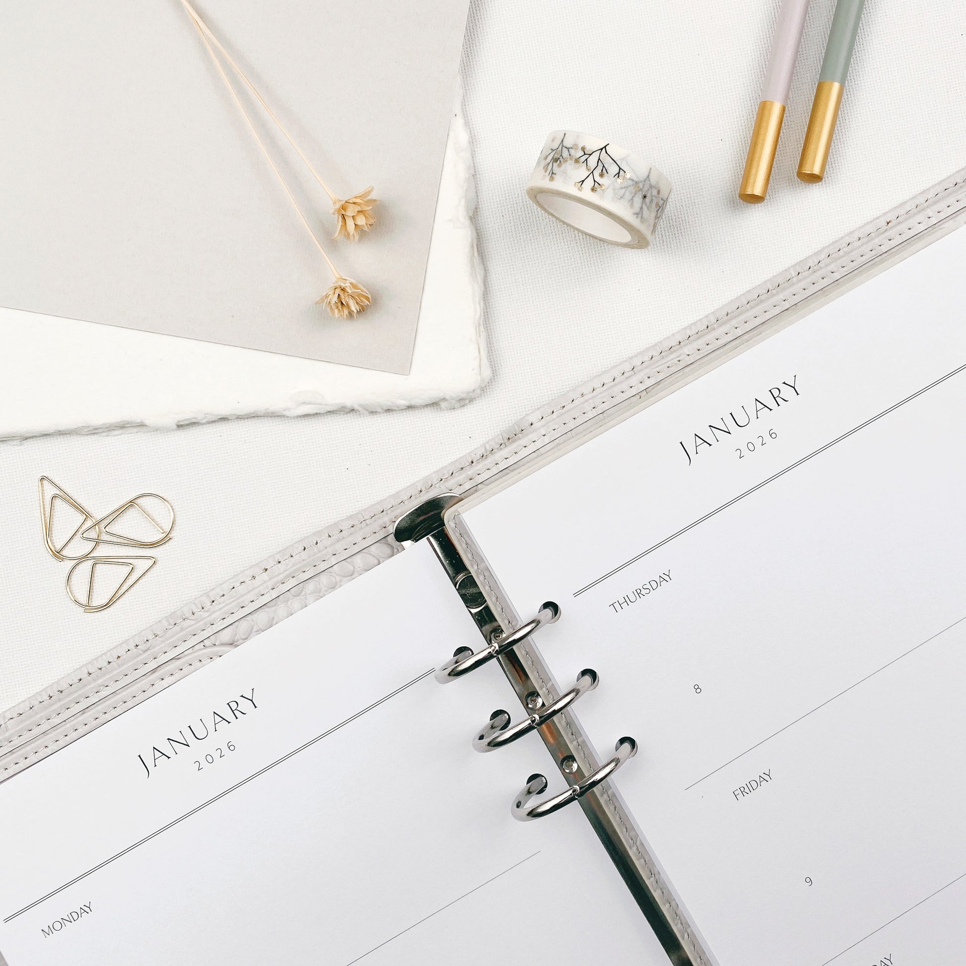 Weekly planner with classic layout  on a white surface with stationery items.