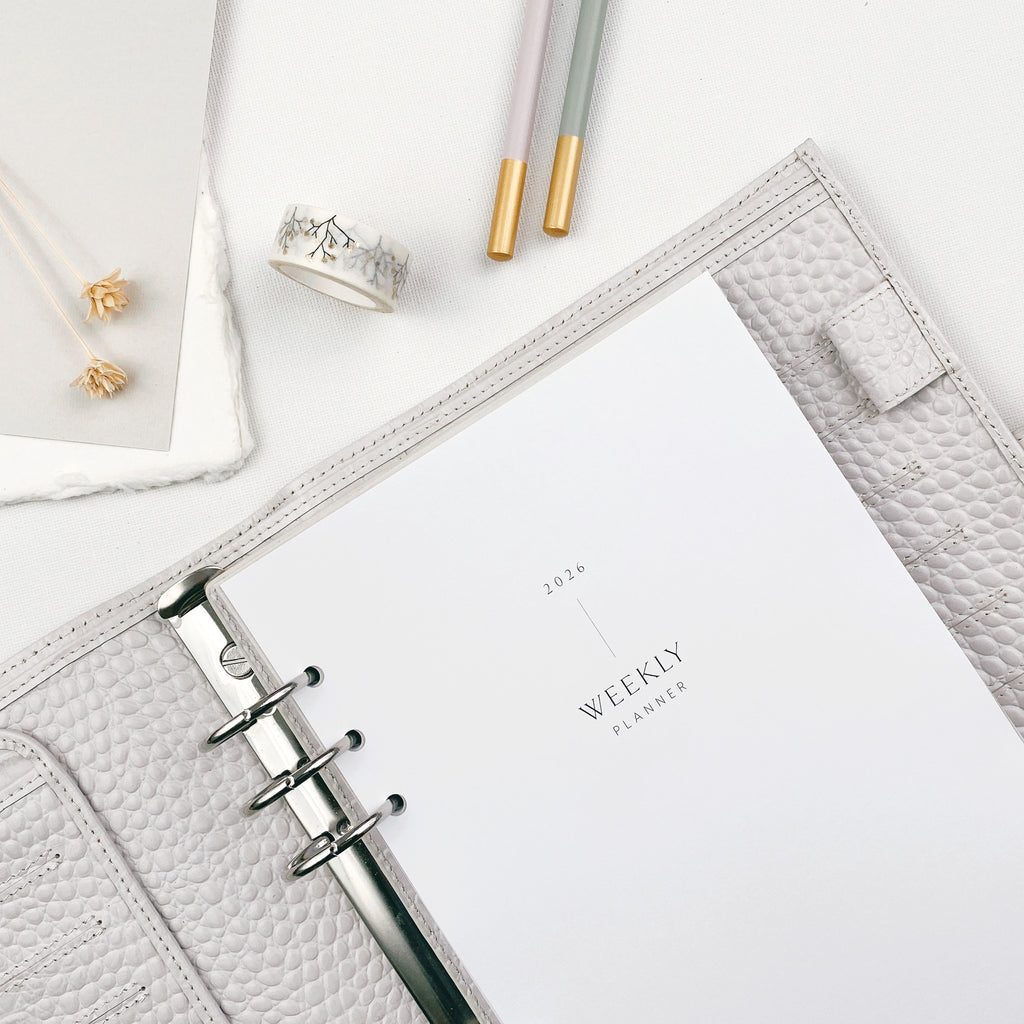 Weekly planner with pencil and washi tape on a white surface