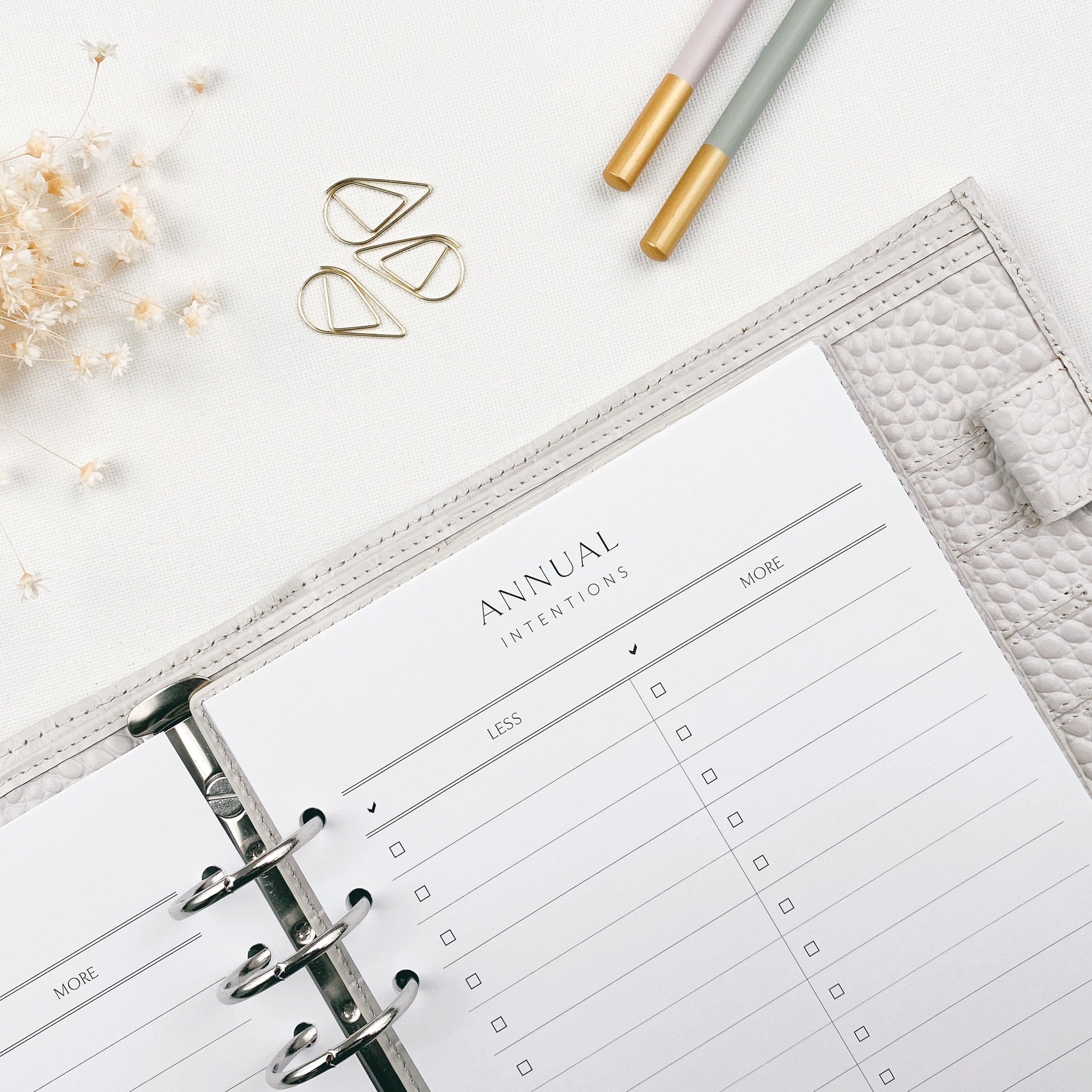 Open planner with 'Annual Intentions' section on a white surface with decorative items.