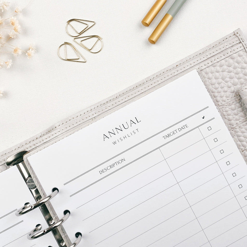 Annual wishlist planner sheet with pencils and decorative items on a white surface