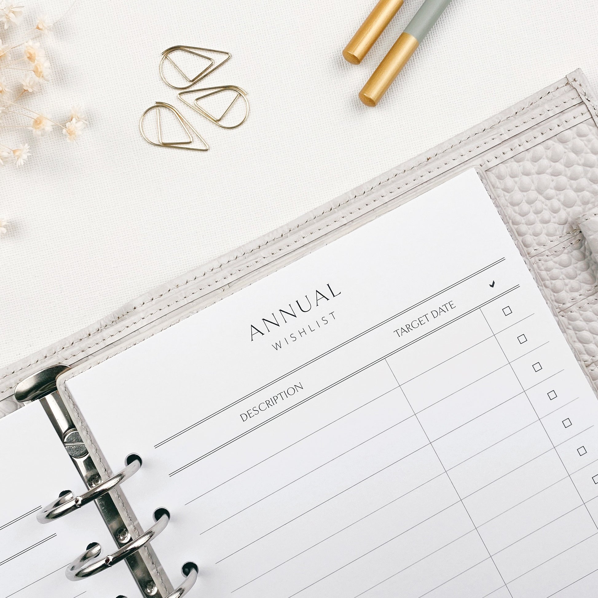 Annual wishlist planner sheet with pencils and decorative items on a white surface