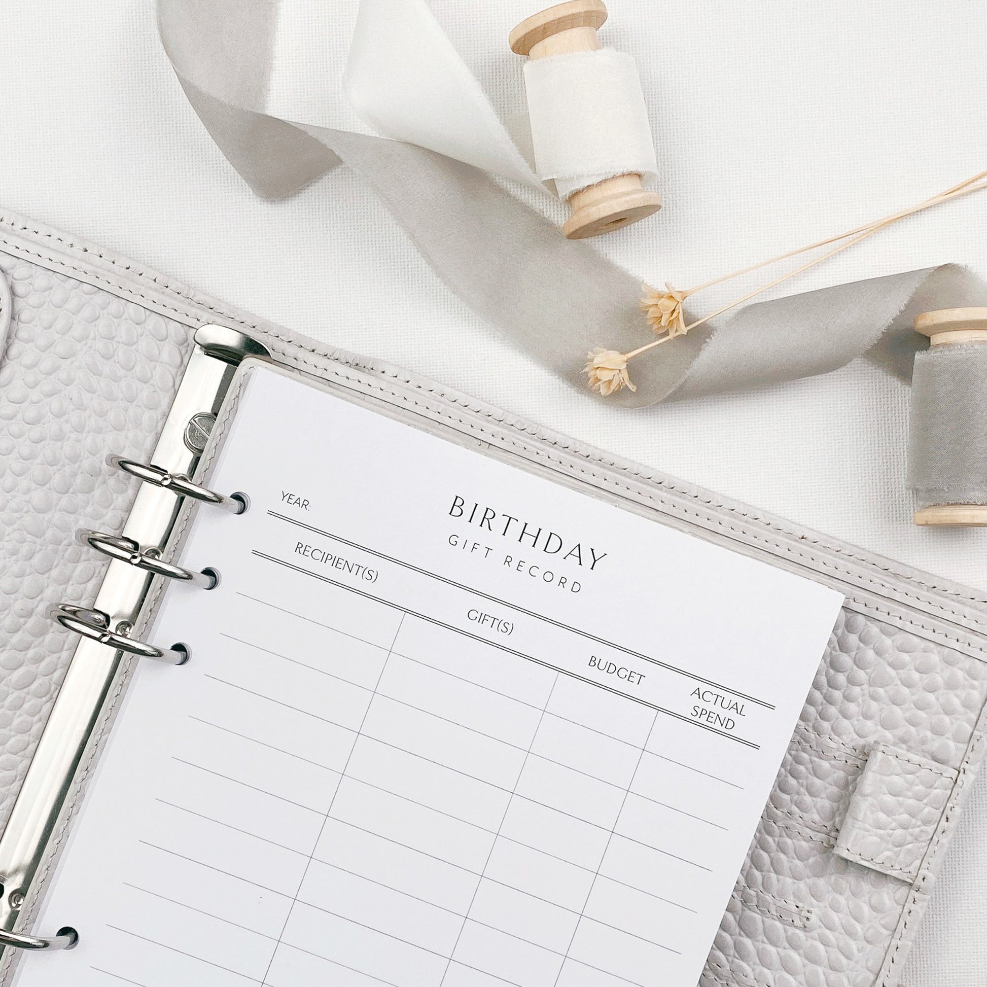 Planner with a birthday gift record page on a white surface with decorative elements.