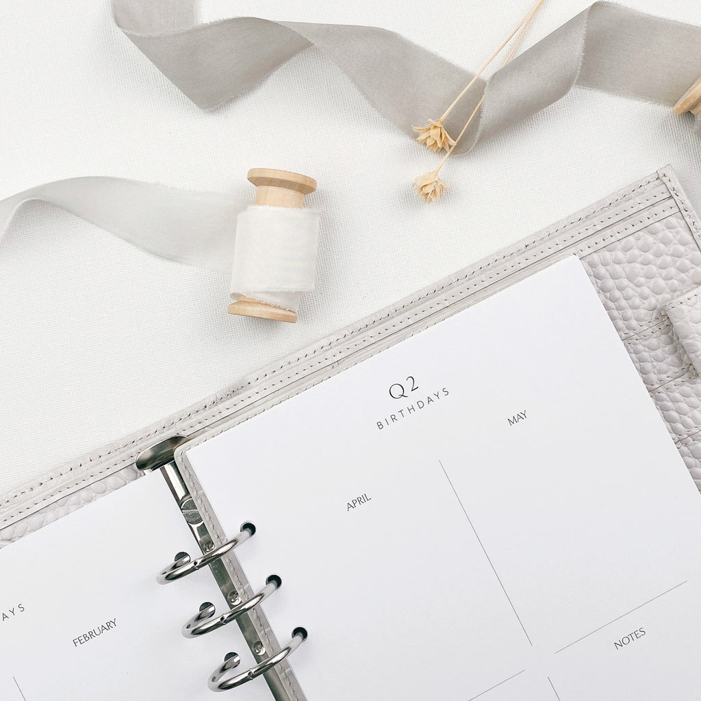 Planner with a white ribbon and decorative elements on a light surface