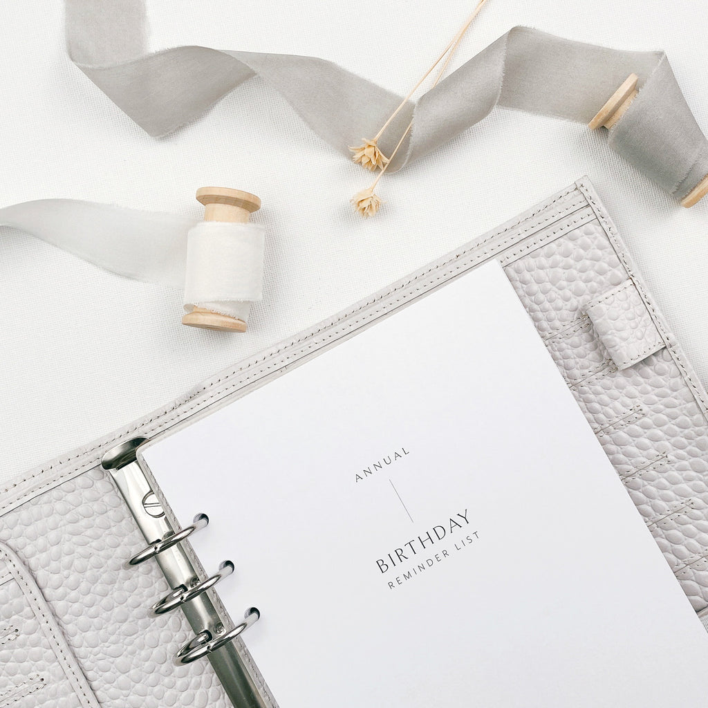 Planner with 'Annual Birthday Reminder List' on a white surface with decorative elements.
