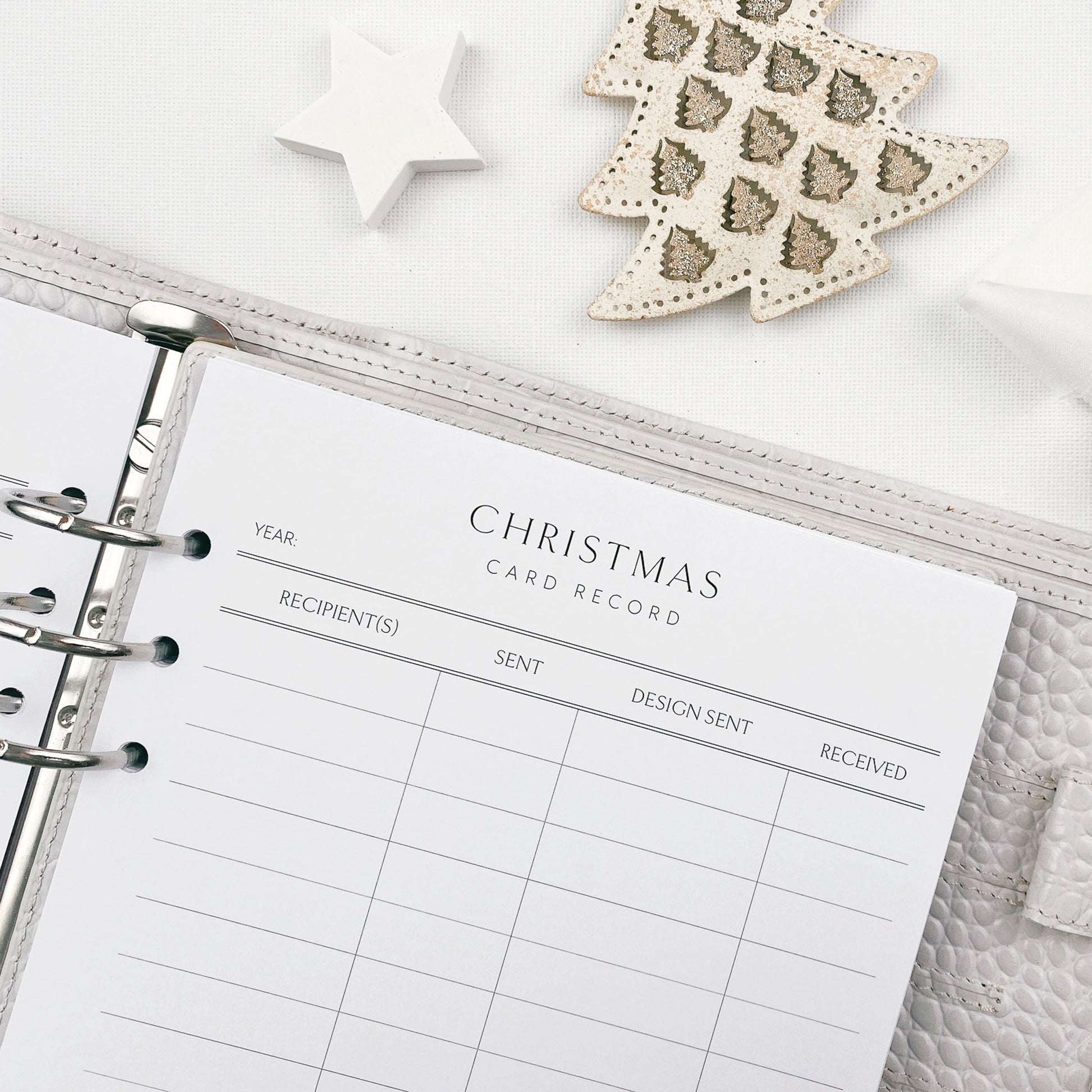 Christmas card tracker record with decorative items on a white surface