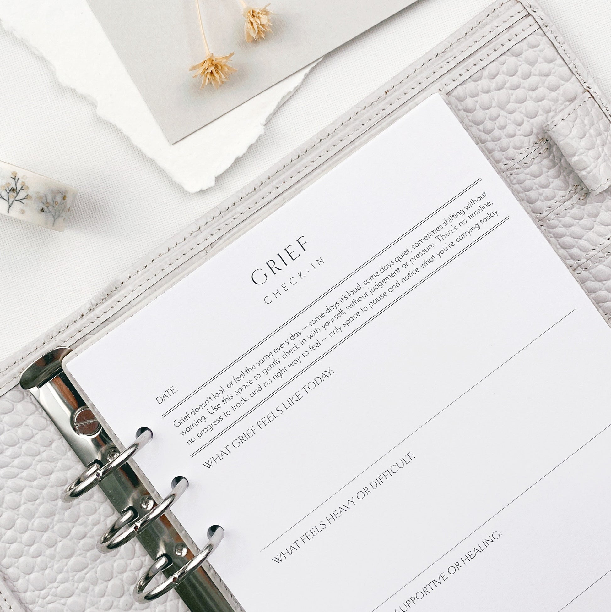 Grief check-in planner page on a white surface with decorative elements