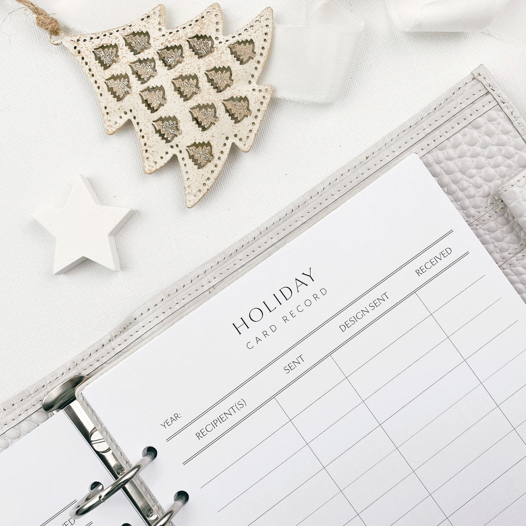 Holiday card record sheet in a planner with decorative tree and star on a white surface