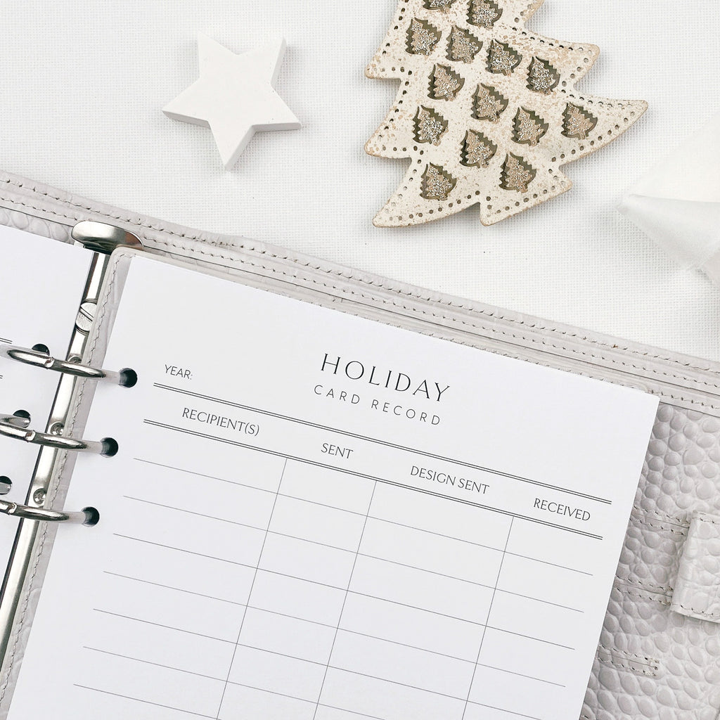 Holiday card record planner insert with decorative Christmas items on a white surface