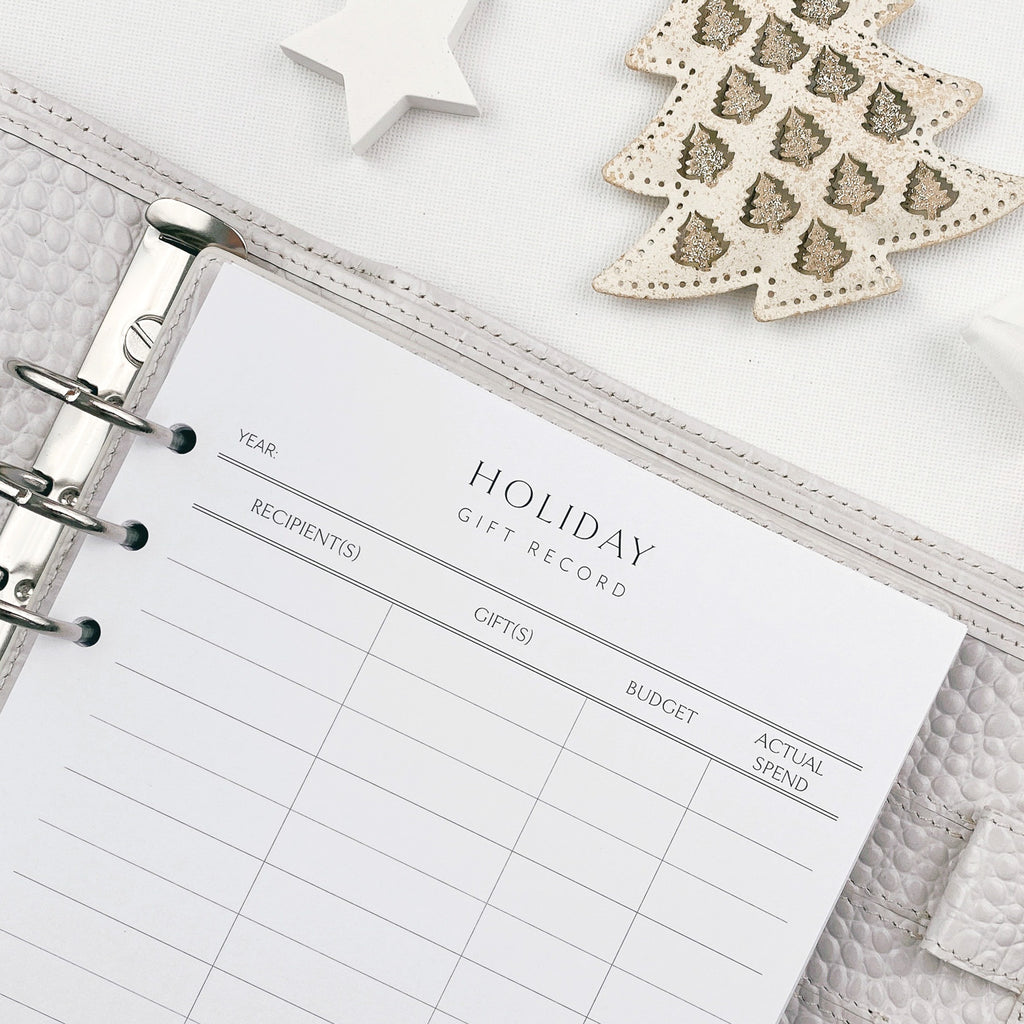 Holiday gift record planner with Christmas decorations on a textured surface
