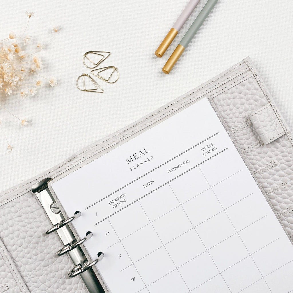Meal planner insert in a grey agenda with decorative elements on a light surface