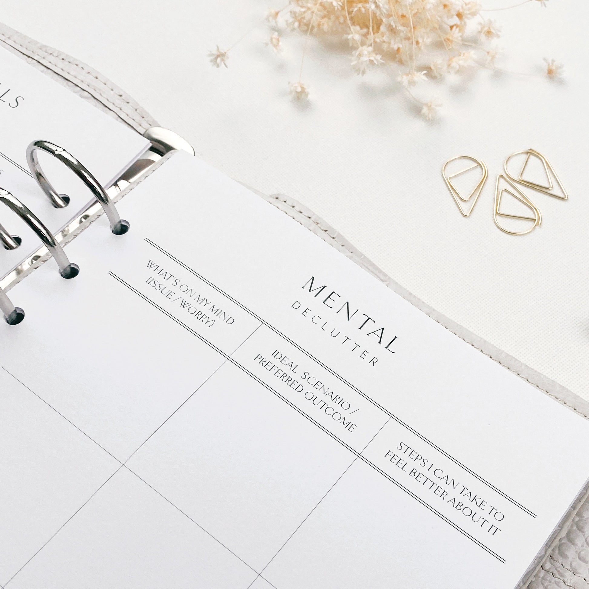 Open planner with 'Mental Declutter' section on a white surface with decorative elements.