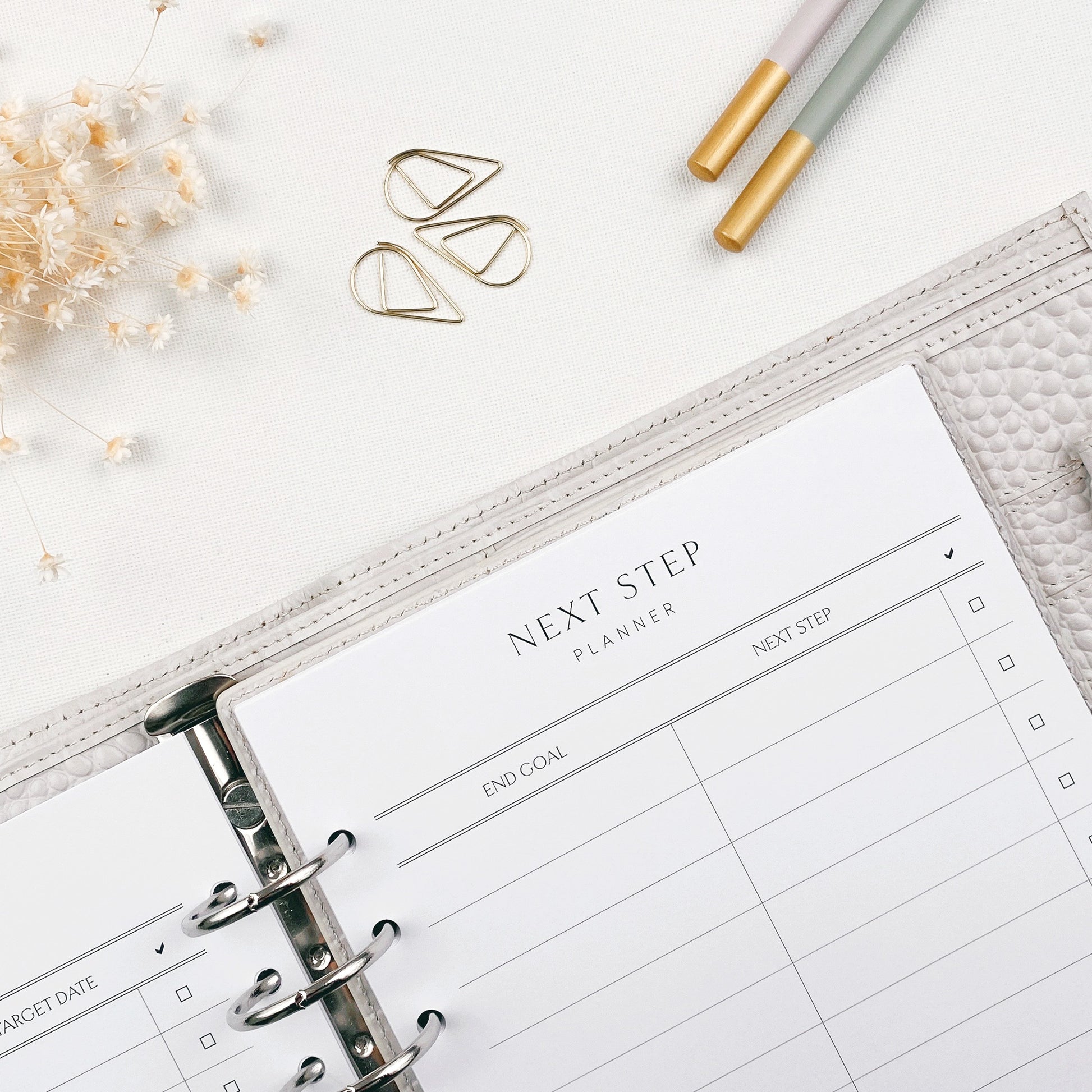 Open planner with 'Next Step' planner title on a white surface with decorative elements.