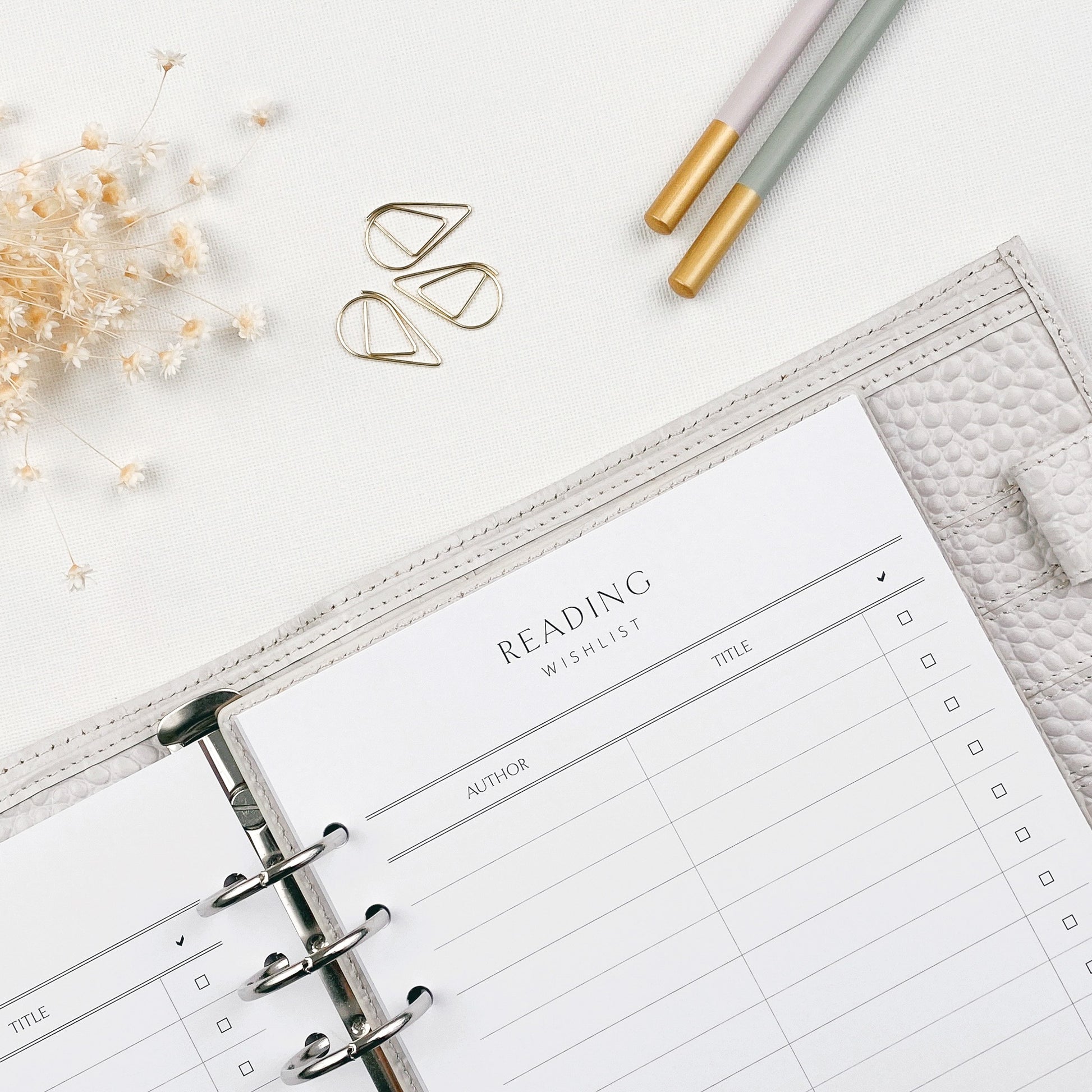 Planner with a reading wishlist section on a white surface with decorative elements.