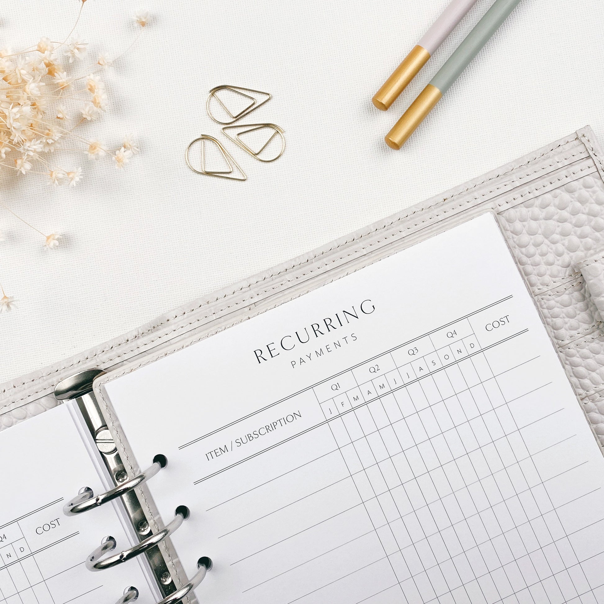 Open planner with 'Recurring Payments' section on a white surface with decorative elements.