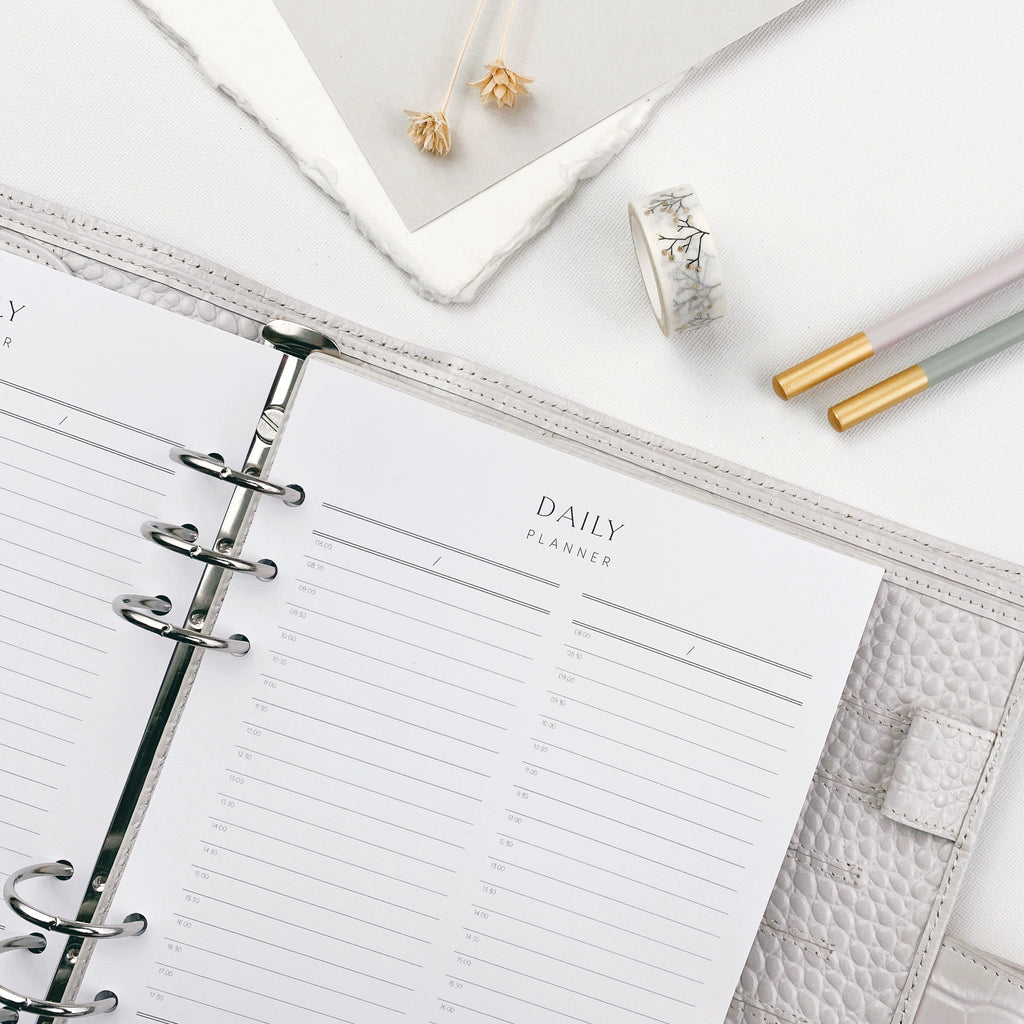Daily planner with pencils and stationery items on a white surface