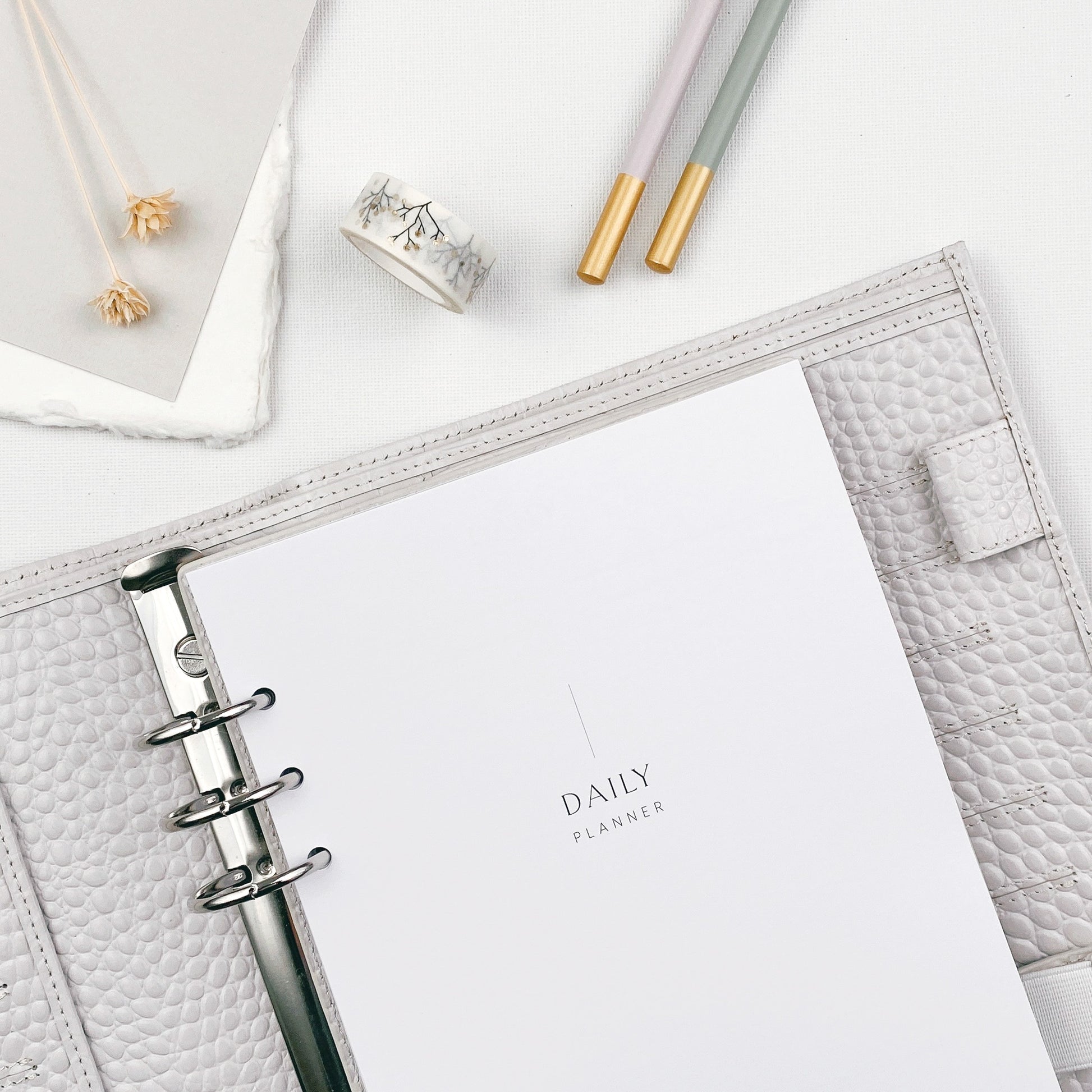 Undated daily planner refills in an organiser on a light surface, surrounded by stationery items.