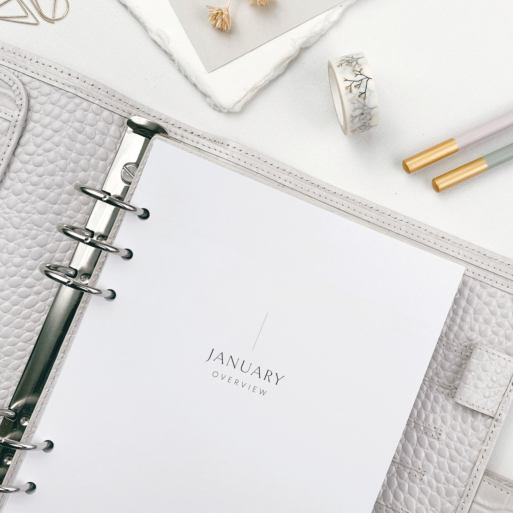 White planner pages with 'January Overview' on a white surface with stationery items.