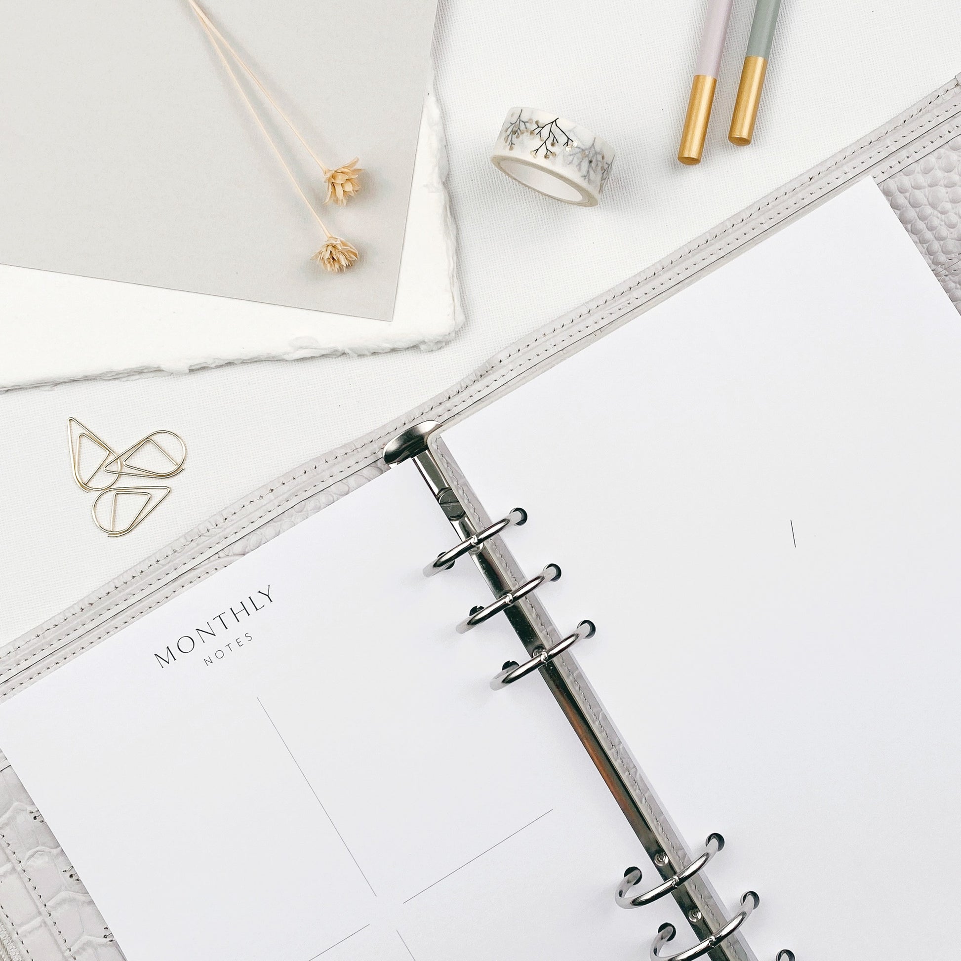 Open planner with monthly layout on a white surface with stationery items.