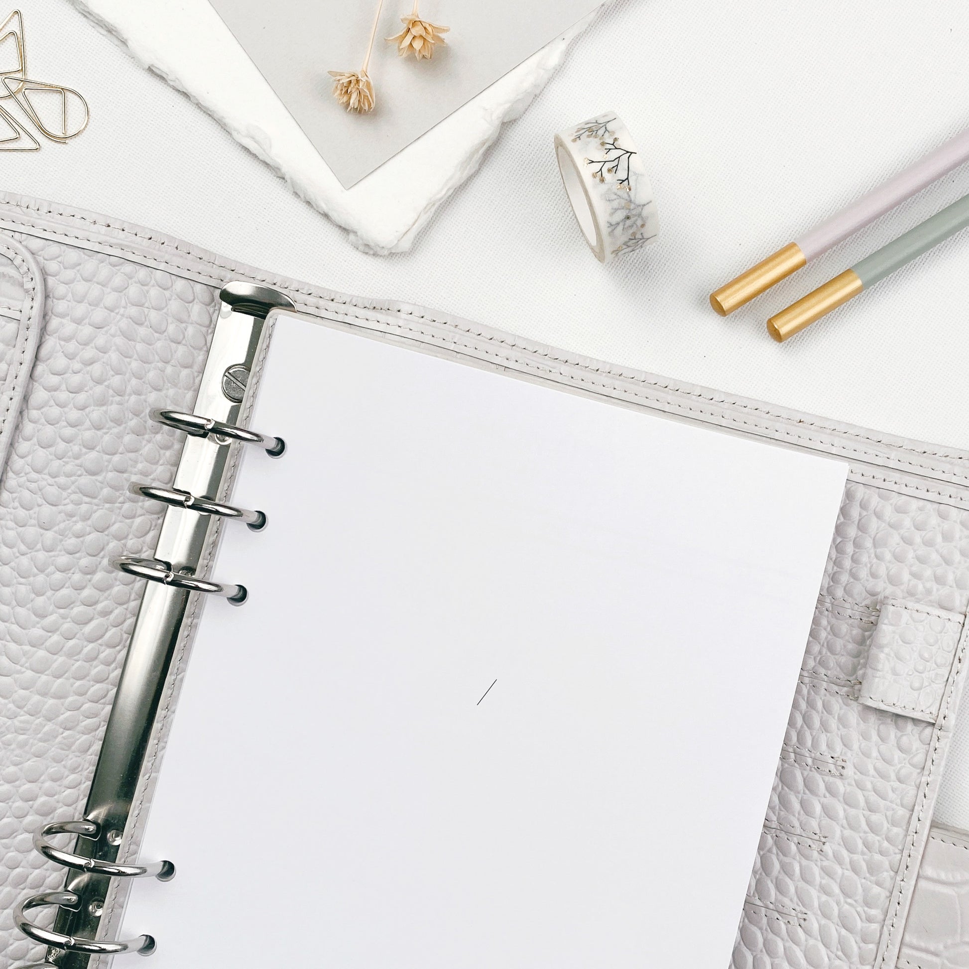 Undated monthly planner with stationery accessories on a white surface