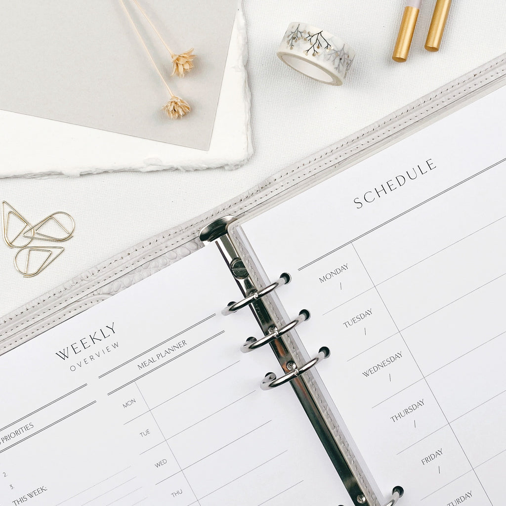 Open planner with weekly schedule on a white surface