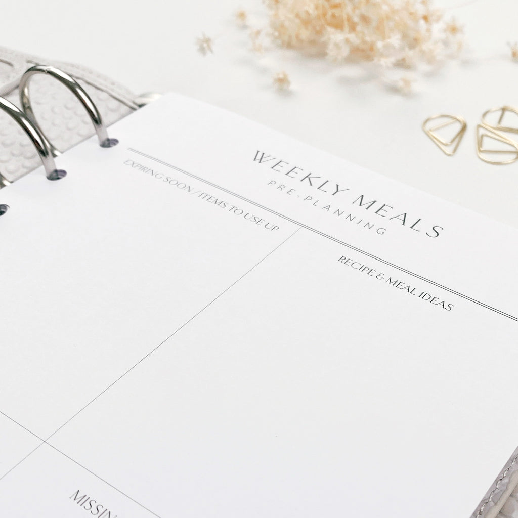 Weekly meals planner with nearby botanicals on a light surface