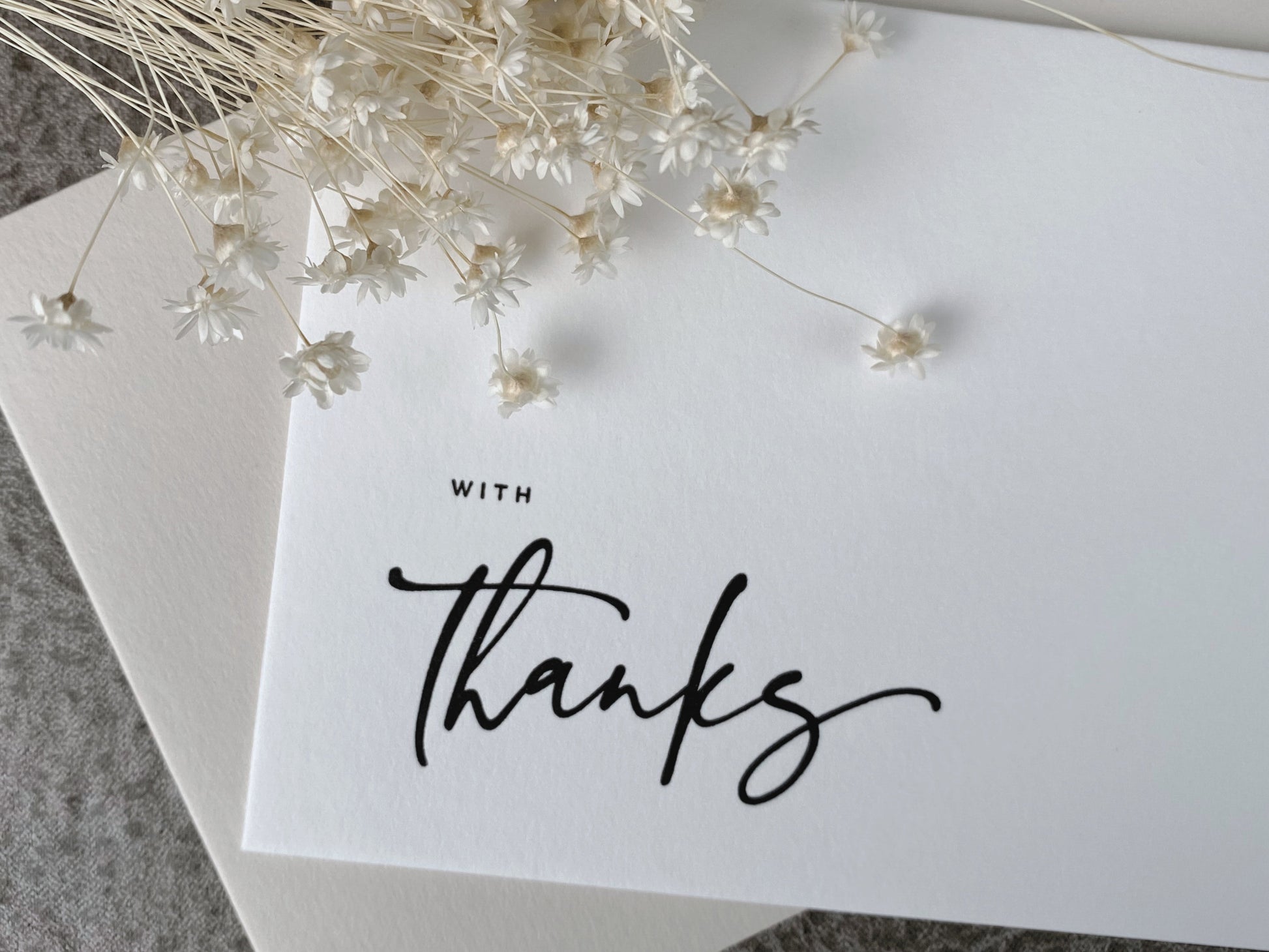 A white letterpress greeting card with the phrase 'With Thanks' printed in black, accompanied by a premium envelope.