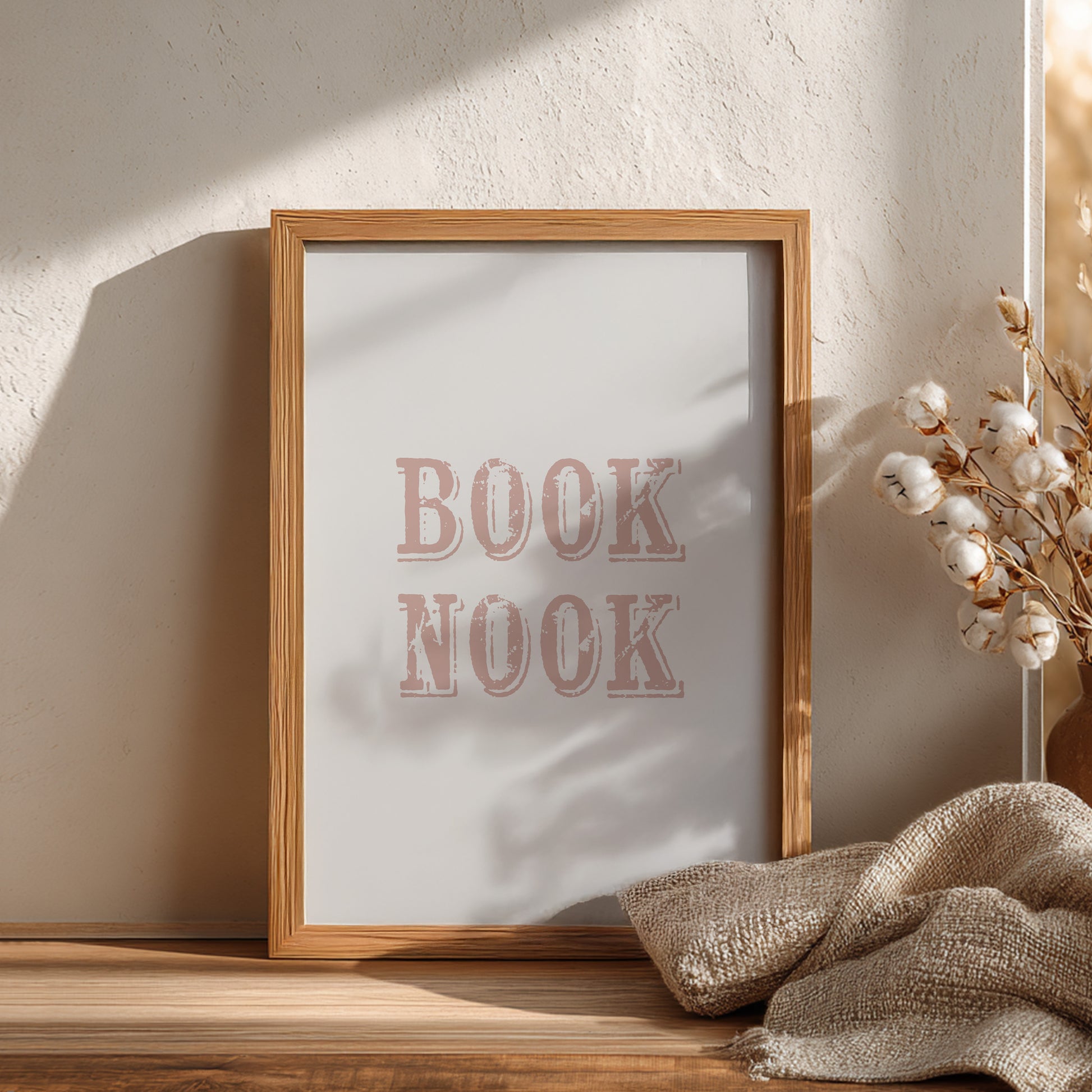 Wooden frame with 'BOOK NOOK' text on a white background, placed on a wooden surface with decorative elements.