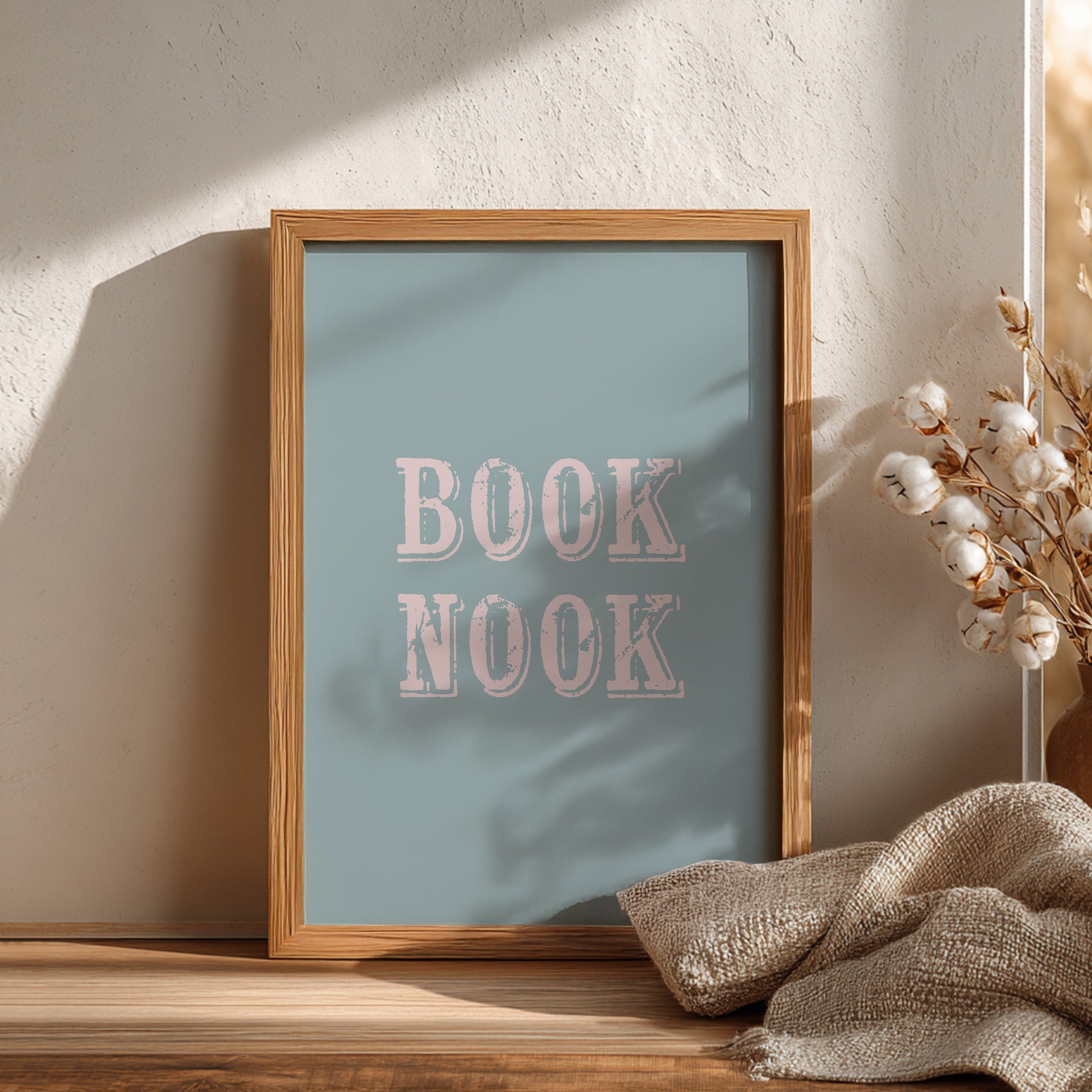 Framed artwork with 'BOOK NOOK' text on a wooden surface with decorative elements.
