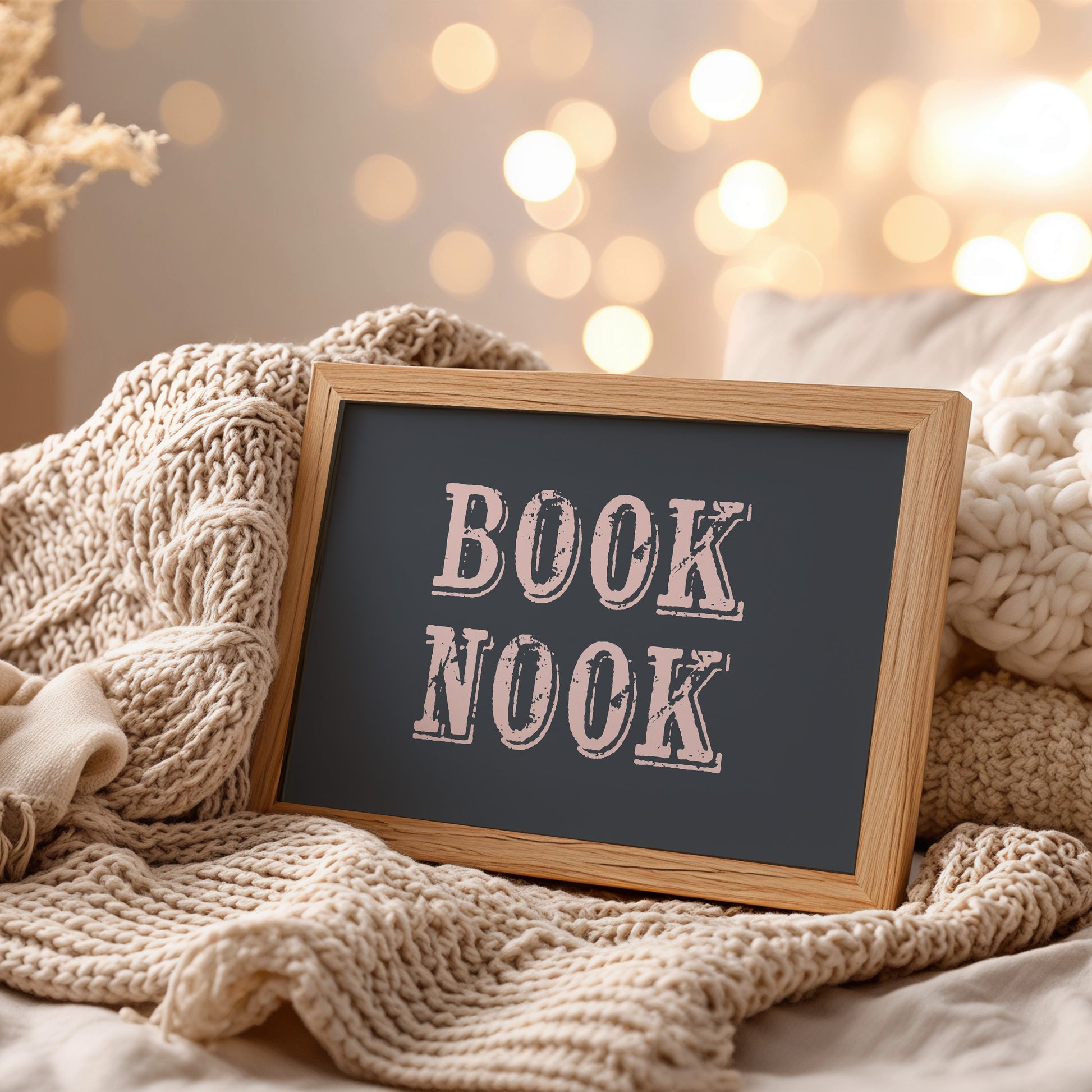 Framed art print with 'BOOK NOOK' text on a cozy setting with knitted textures and soft lighting.