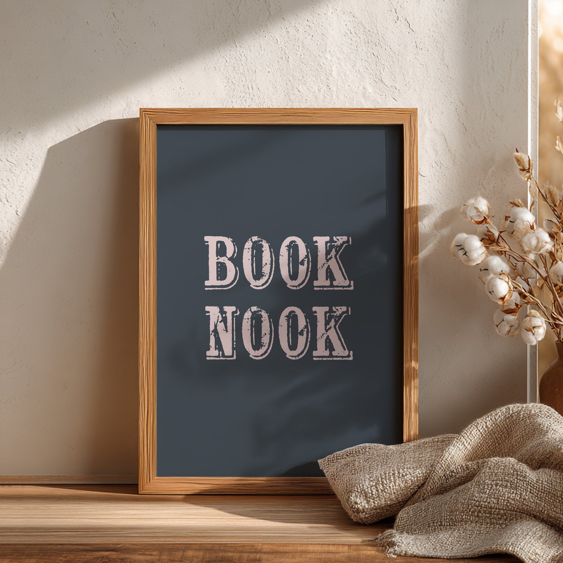 Framed artwork with 'BOOK NOOK' text on a wooden surface with decorative elements.