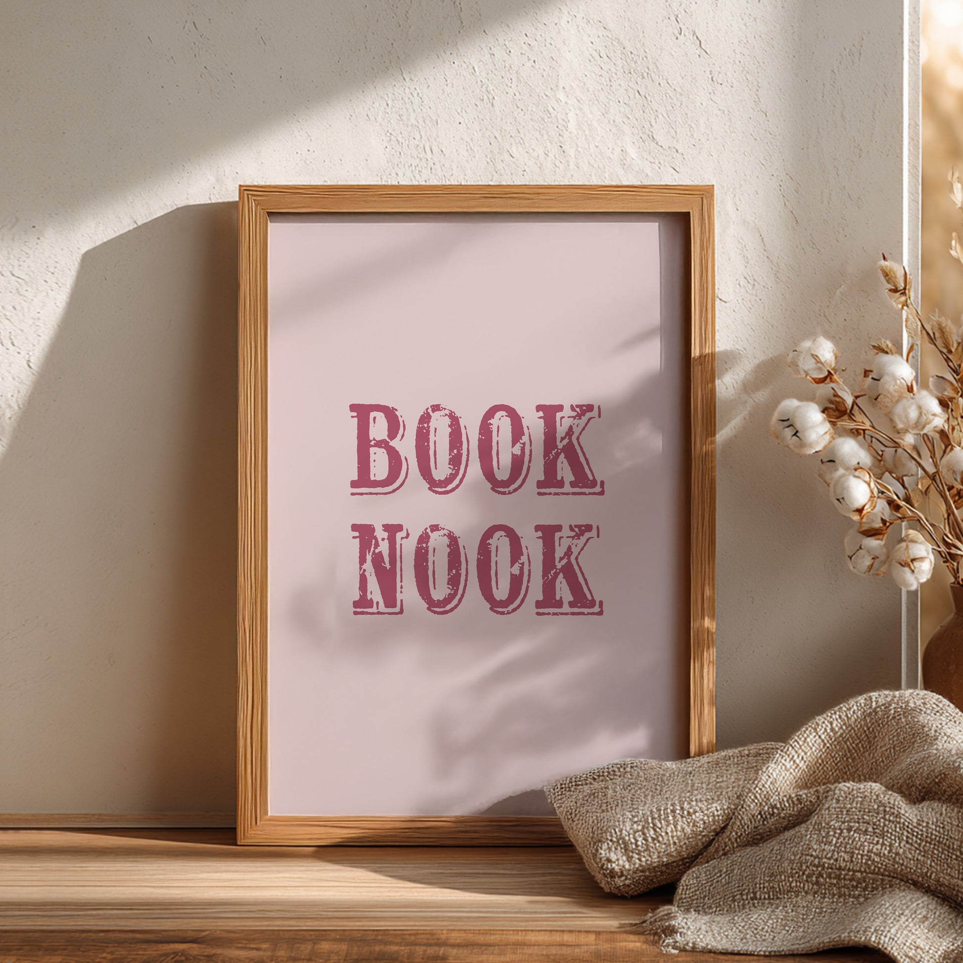 Framed print with 'BOOK NOOK' text on a wooden surface with decorative elements.