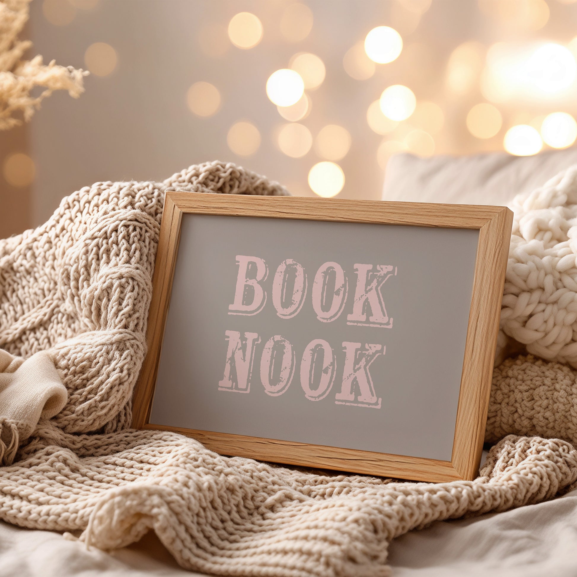 Decorative sign with 'BOOK NOOK' text on a cozy blanket with blurred lights in the background