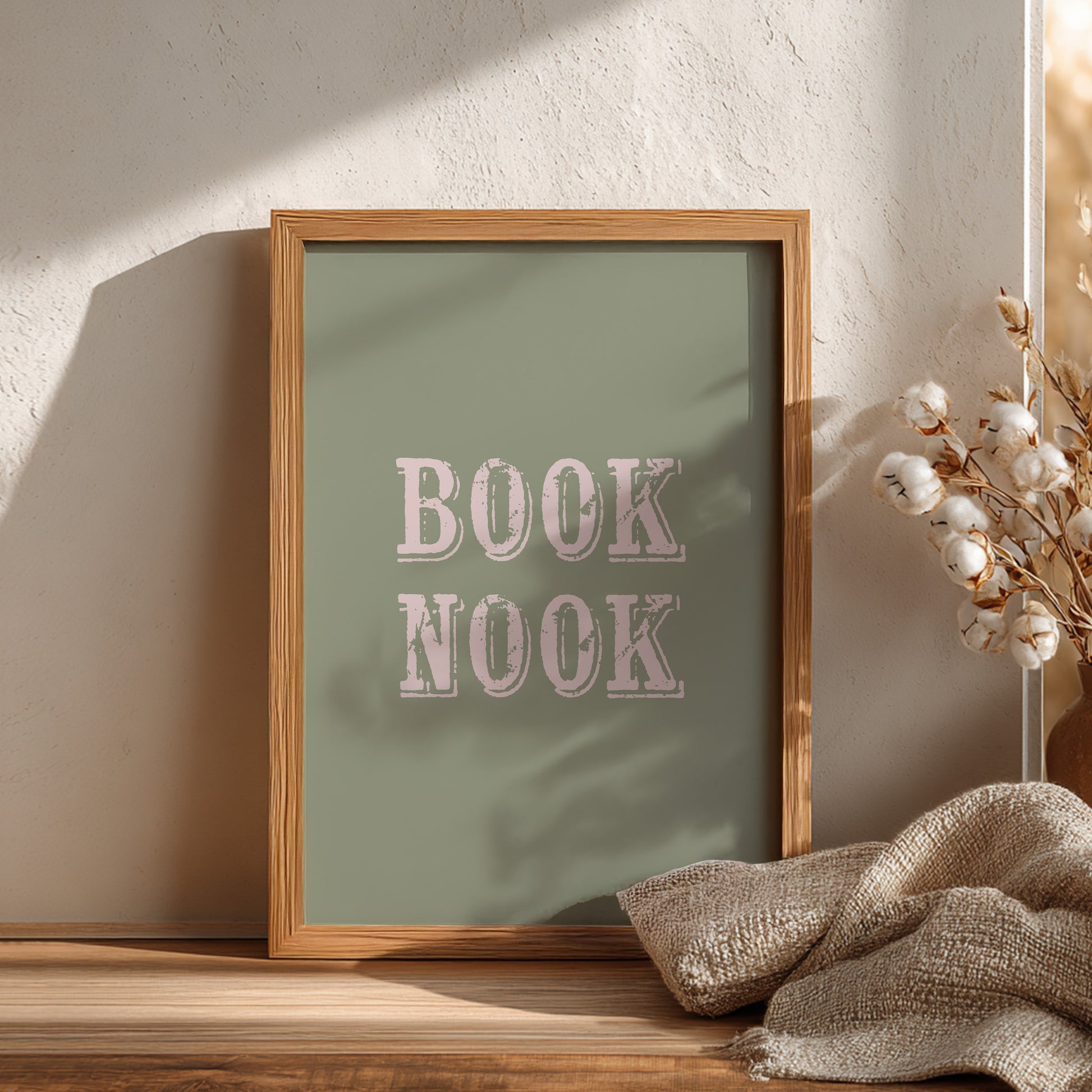 Framed artwork with 'BOOK NOOK' text on a wooden surface with decorative elements.