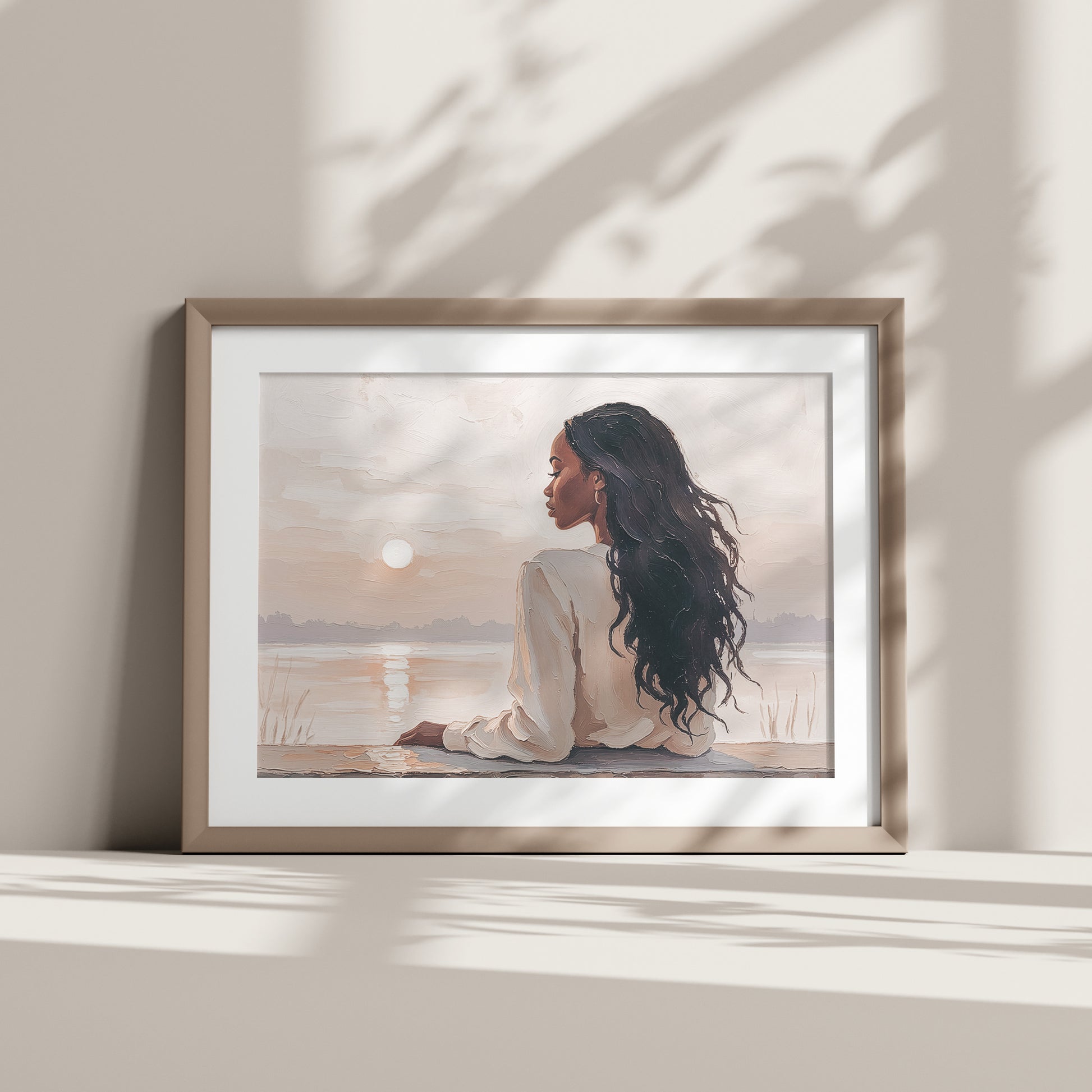 Artwork of a woman resting by the warer with a sunset, on a light-colored wall.