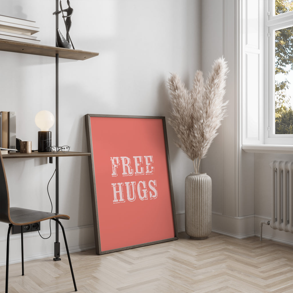 Room interior with a 'FREE HUGS' poster on a wall, a shelf with books and decor, and a vase with dried plants.